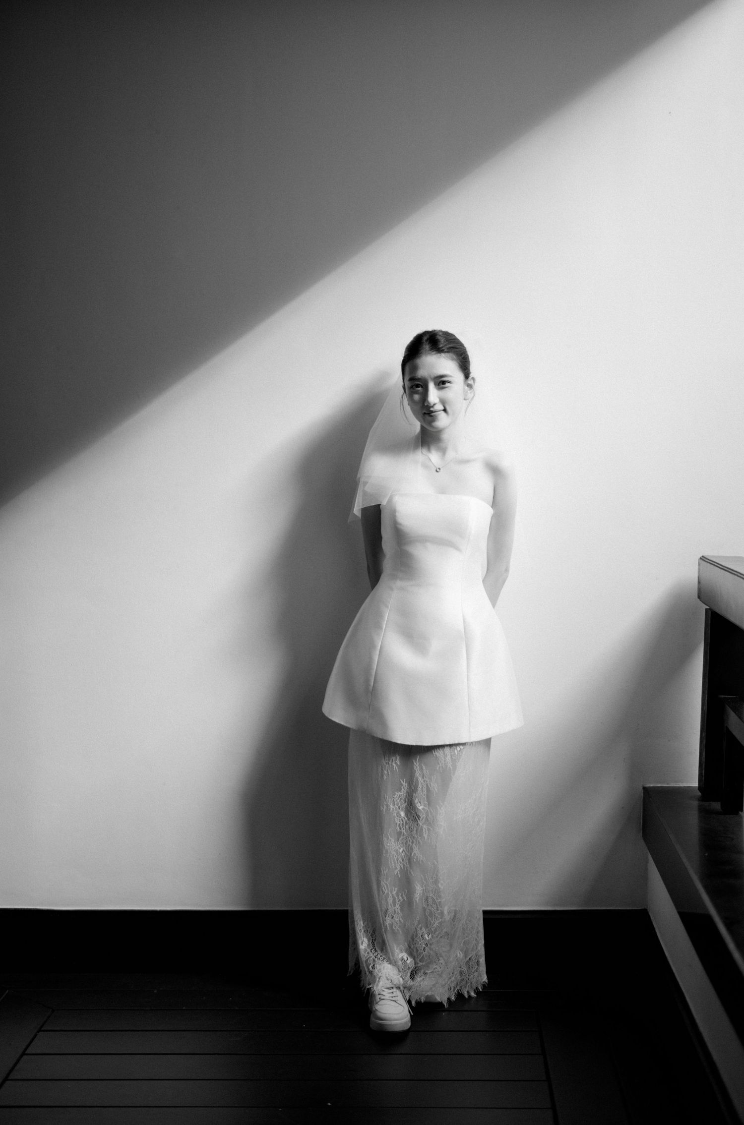Series of artistic black and white bridal gown portraits against white wall with dramatic shadows.