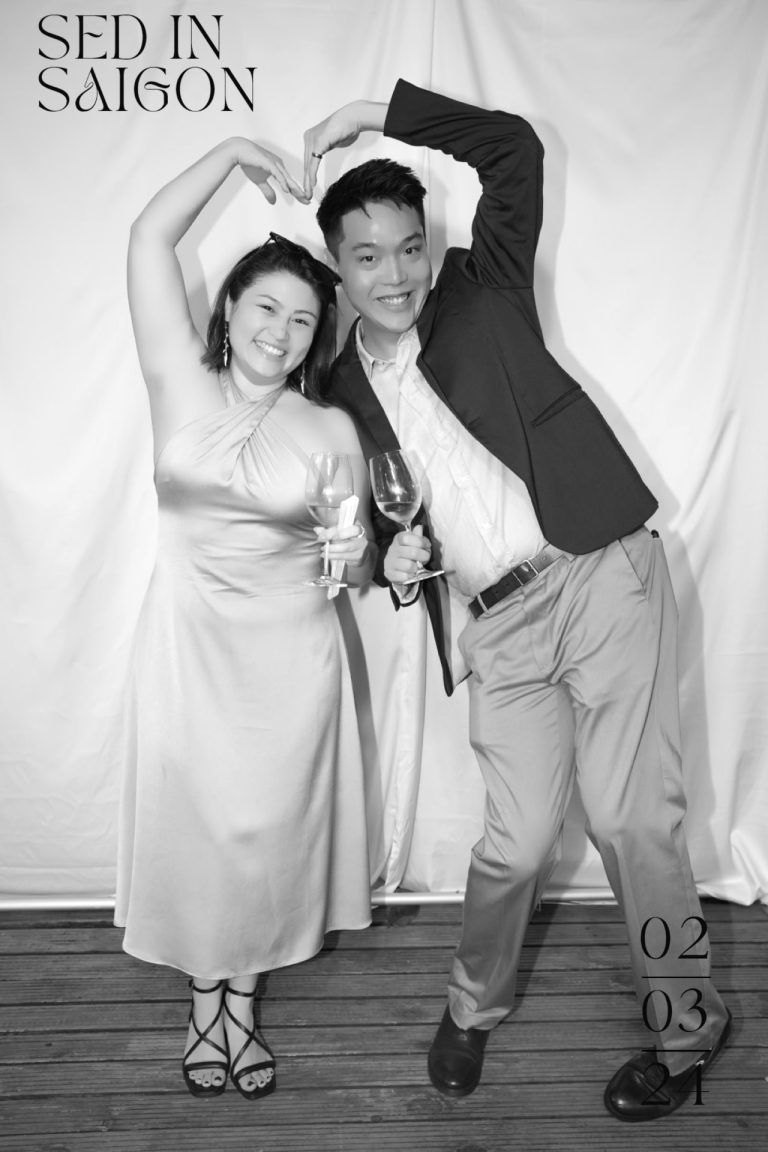A vintage-style studio portrait with two people forming a heart shape against white backdrop.