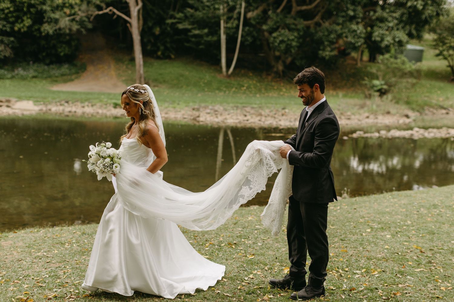 Bride's white dress and veil flow gracefully during outdoor wedding portrait session.