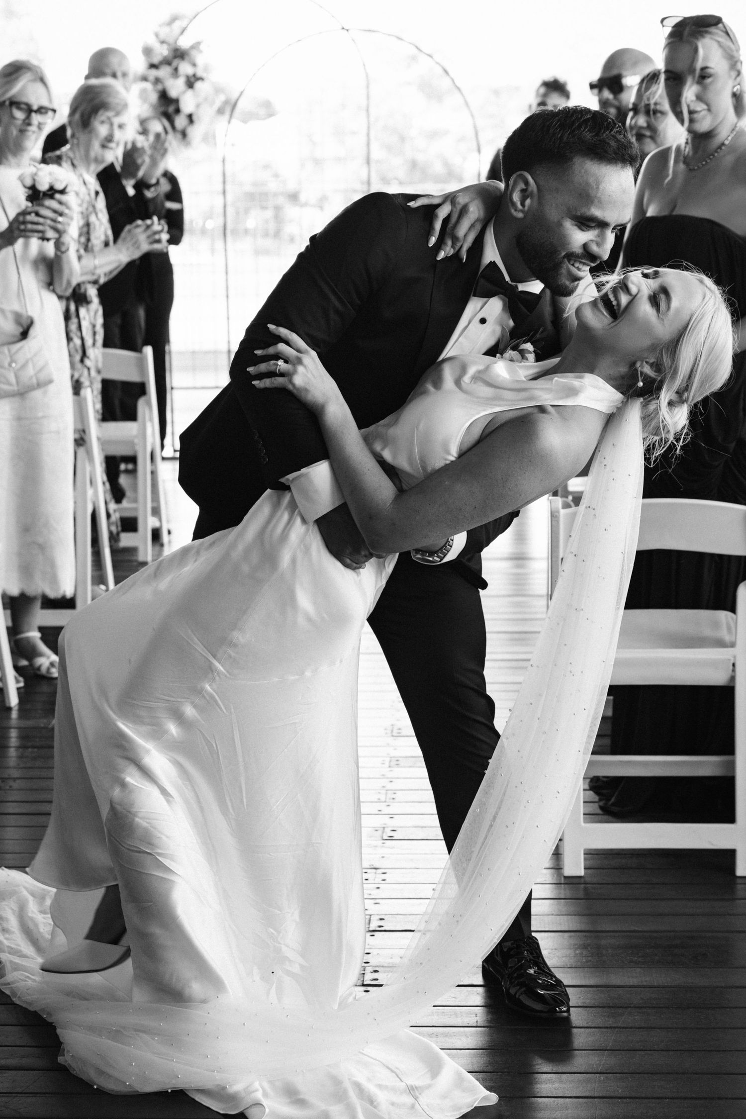 Romantic black and white wedding photo of couple sharing intimate dance moment on deck.