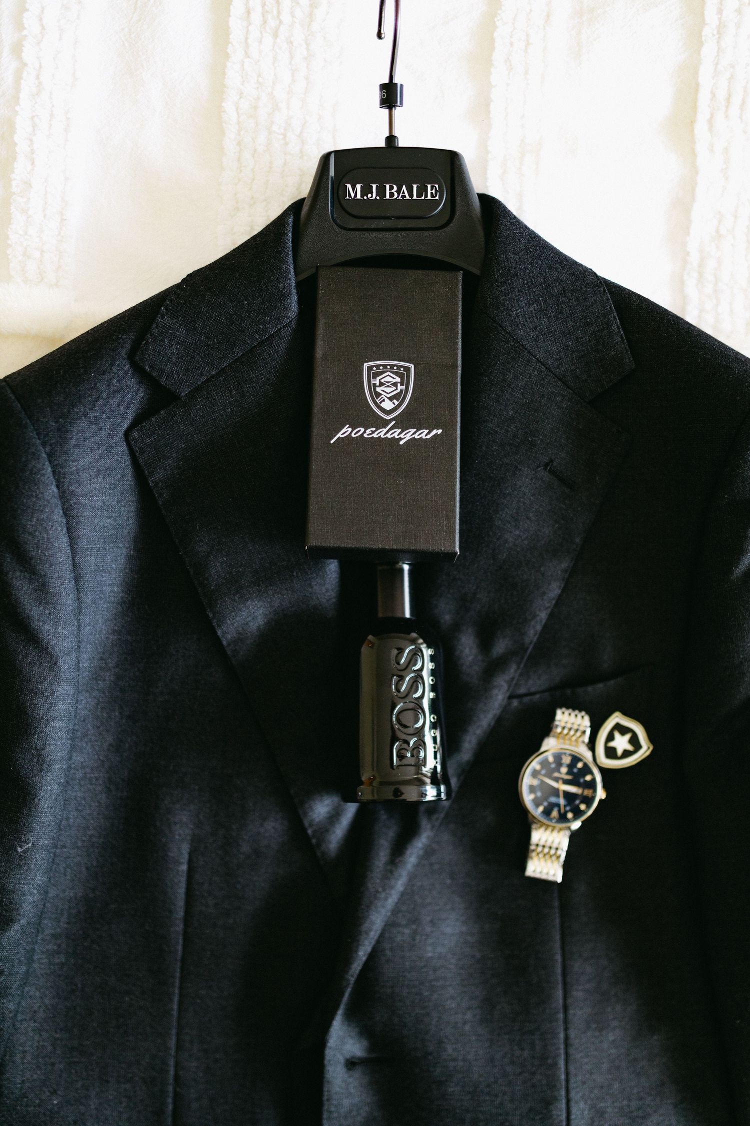 Close-up view of black suit lapels with decorative silver pins and brooches against dark fabric.