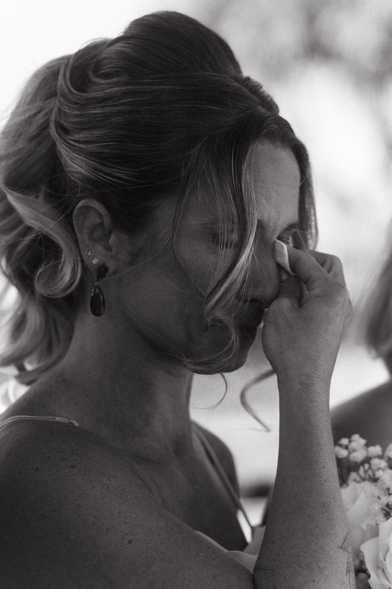 Black and white close-up of emotional wedding attendees wiping tears.