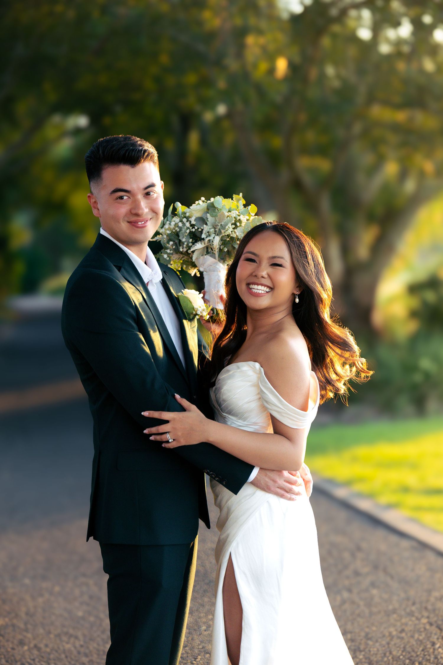 A couple in wedding attire poses playfully outdoors during a sunset photoshoot.