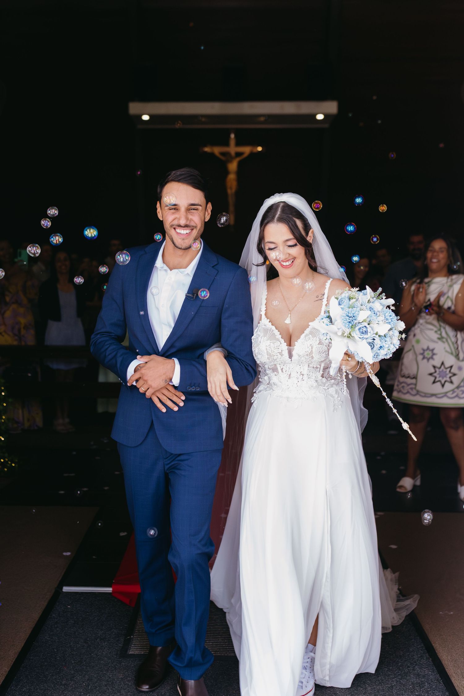 A couple celebrates their wedding day, with the bride in a white dress and groom in a navy blue suit.