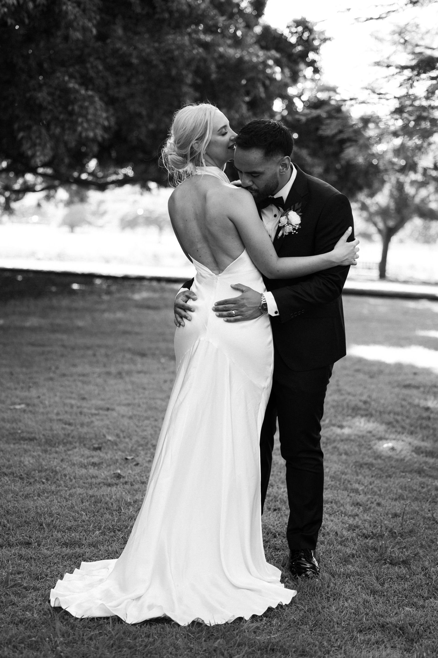 A black and white series of wedding portraits showing tender embraces between newlyweds on a grassy field.