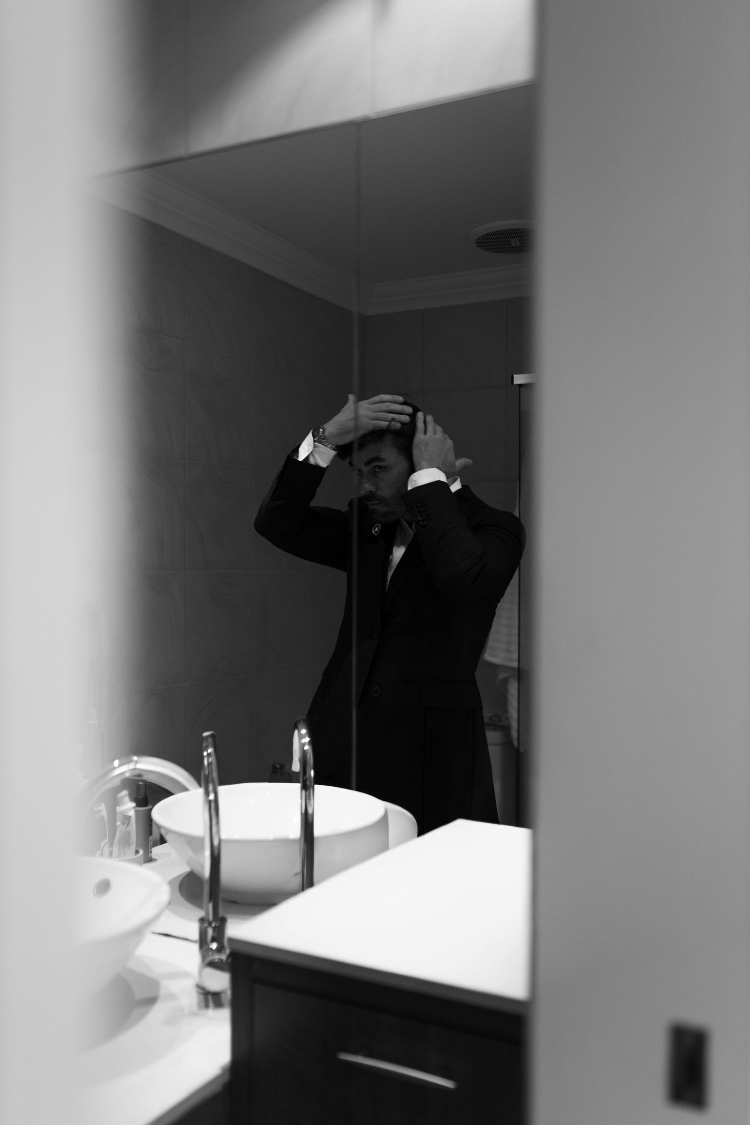 Artistic black and white silhouette of wedding preparation in bathroom mirror.