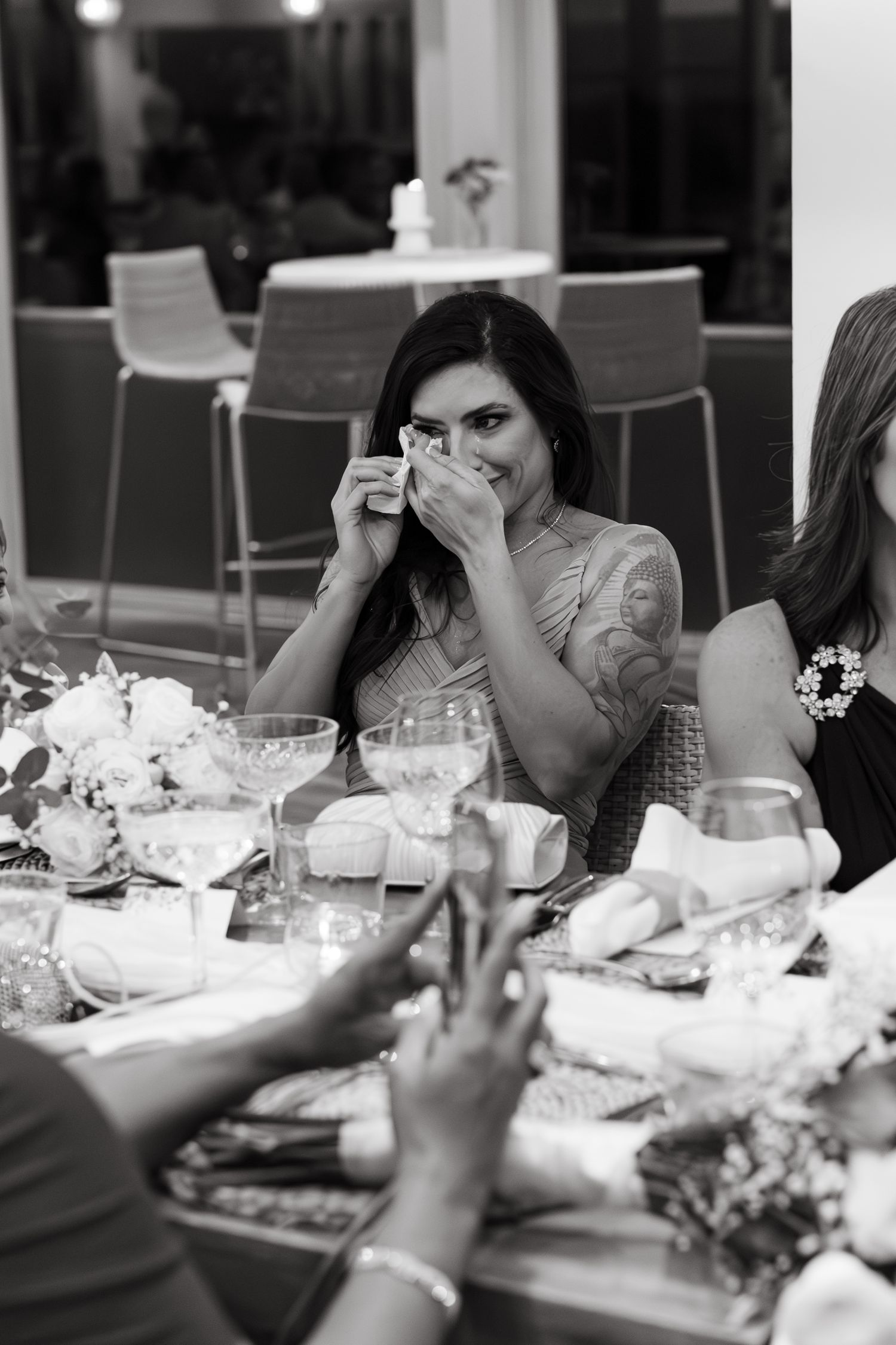 Black and white photo of dinner guests wiping tears at reception tables.