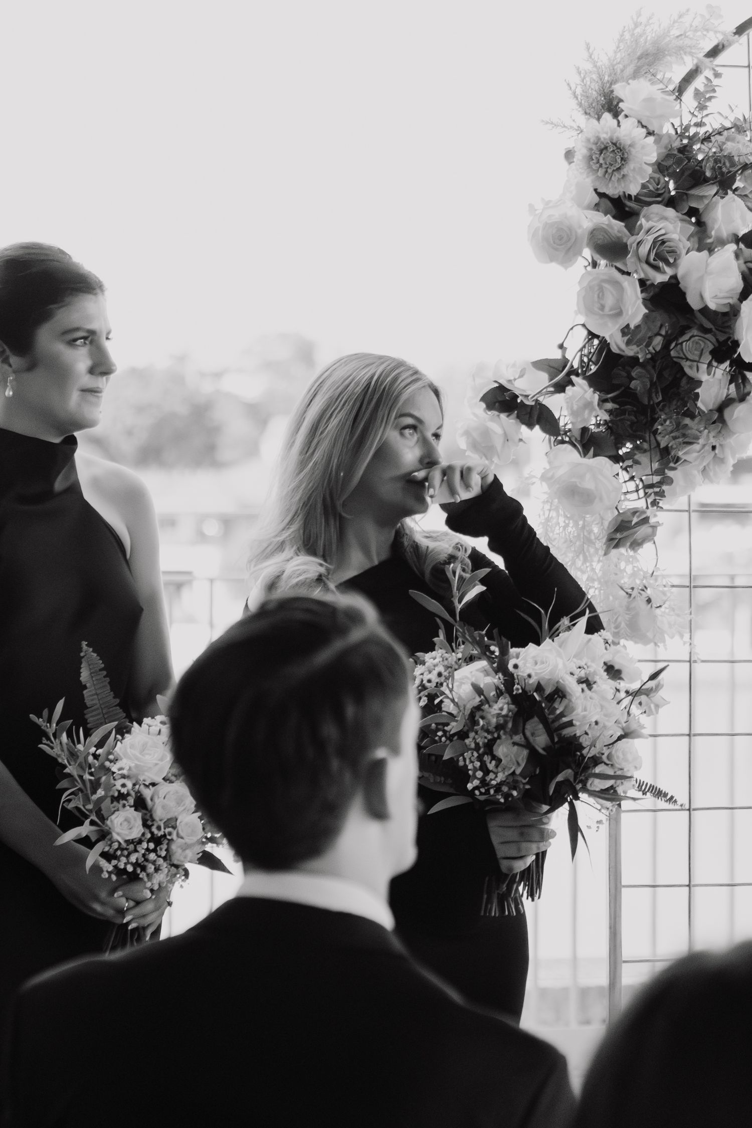 A black and white photo series showing a couple in silhouette by a window with white floral arrangements.