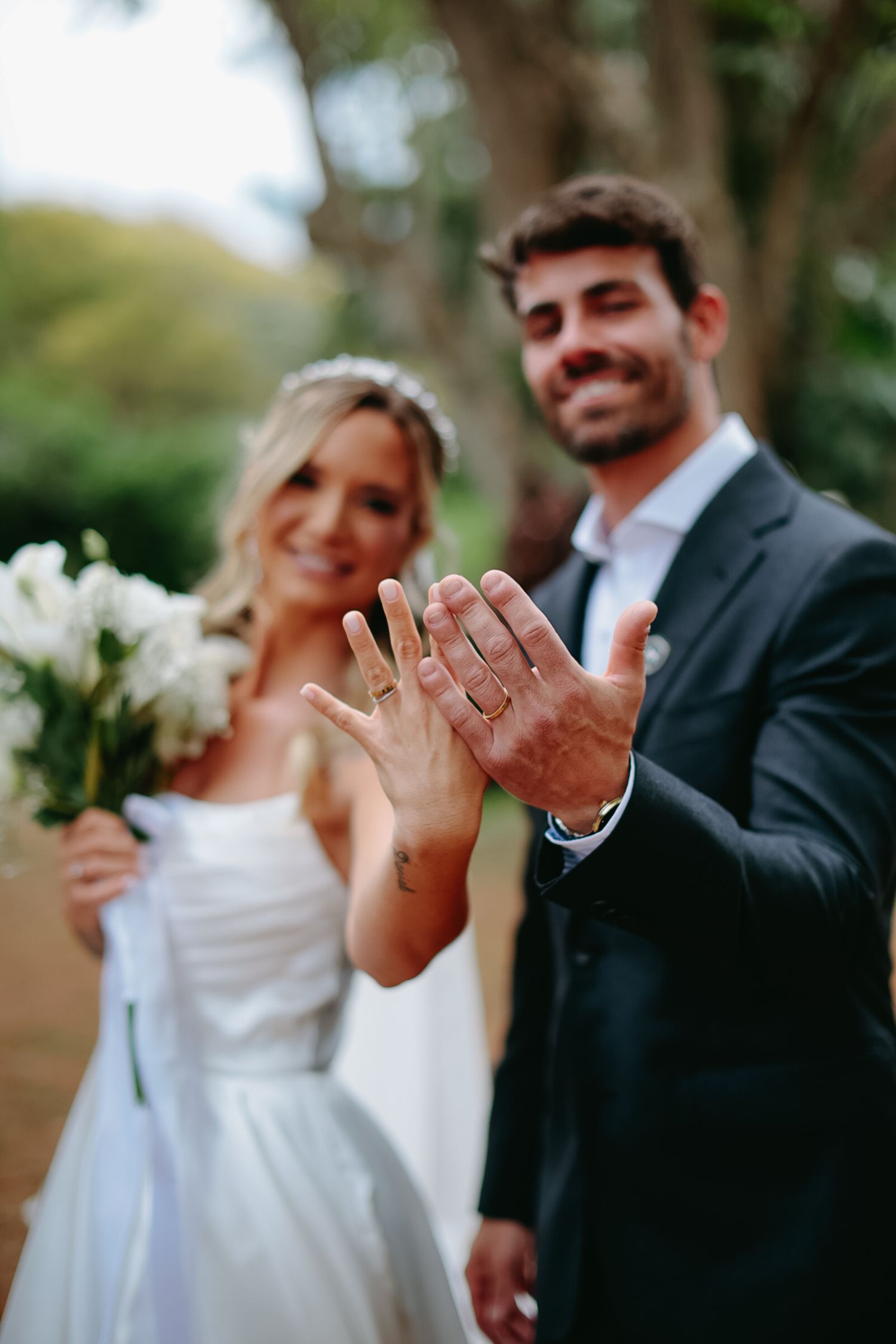 Wedding couple shows off their rings in candid outdoor portrait sequence.