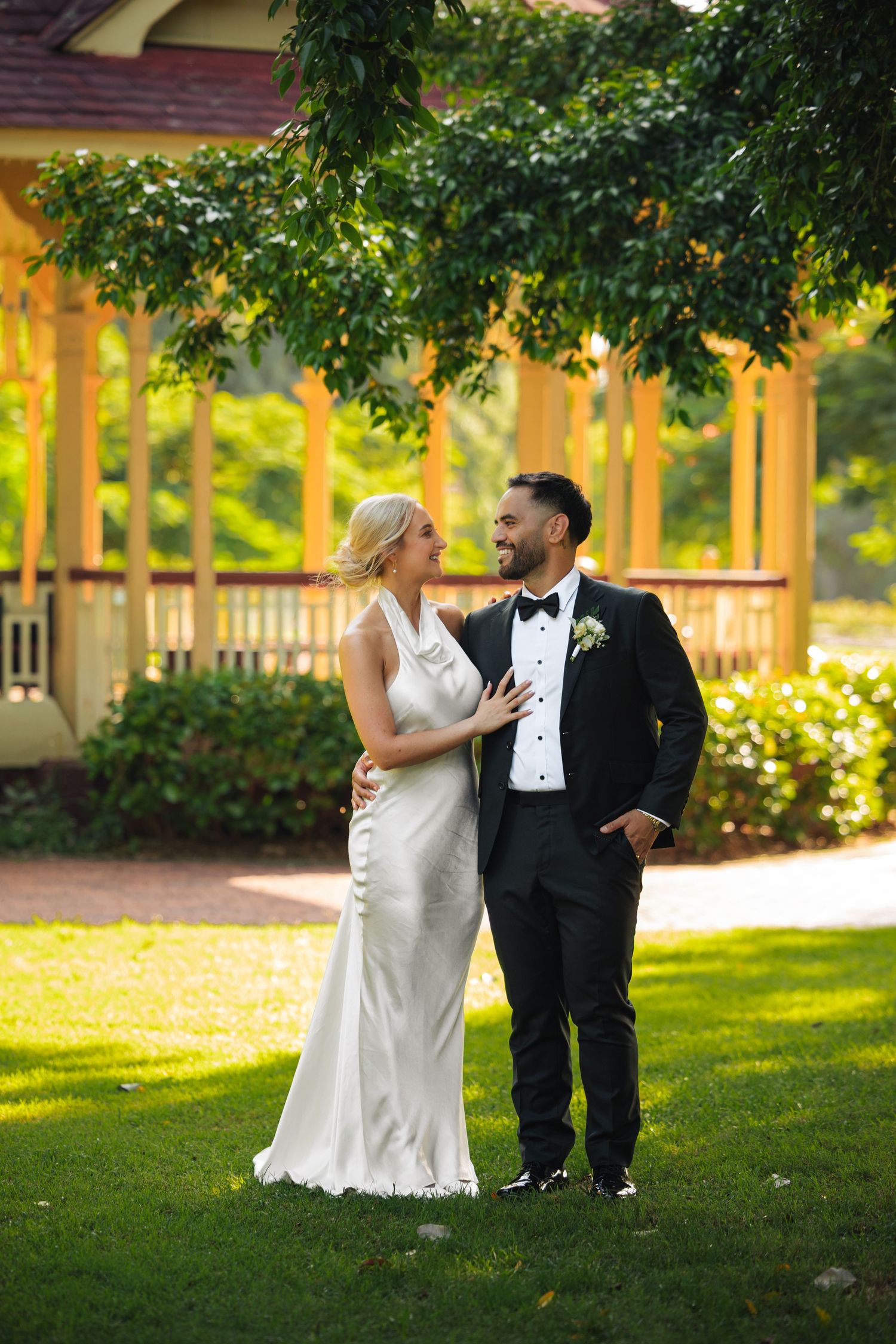 A romantic wedding couple shares playful moments in a lush garden setting during golden hour.