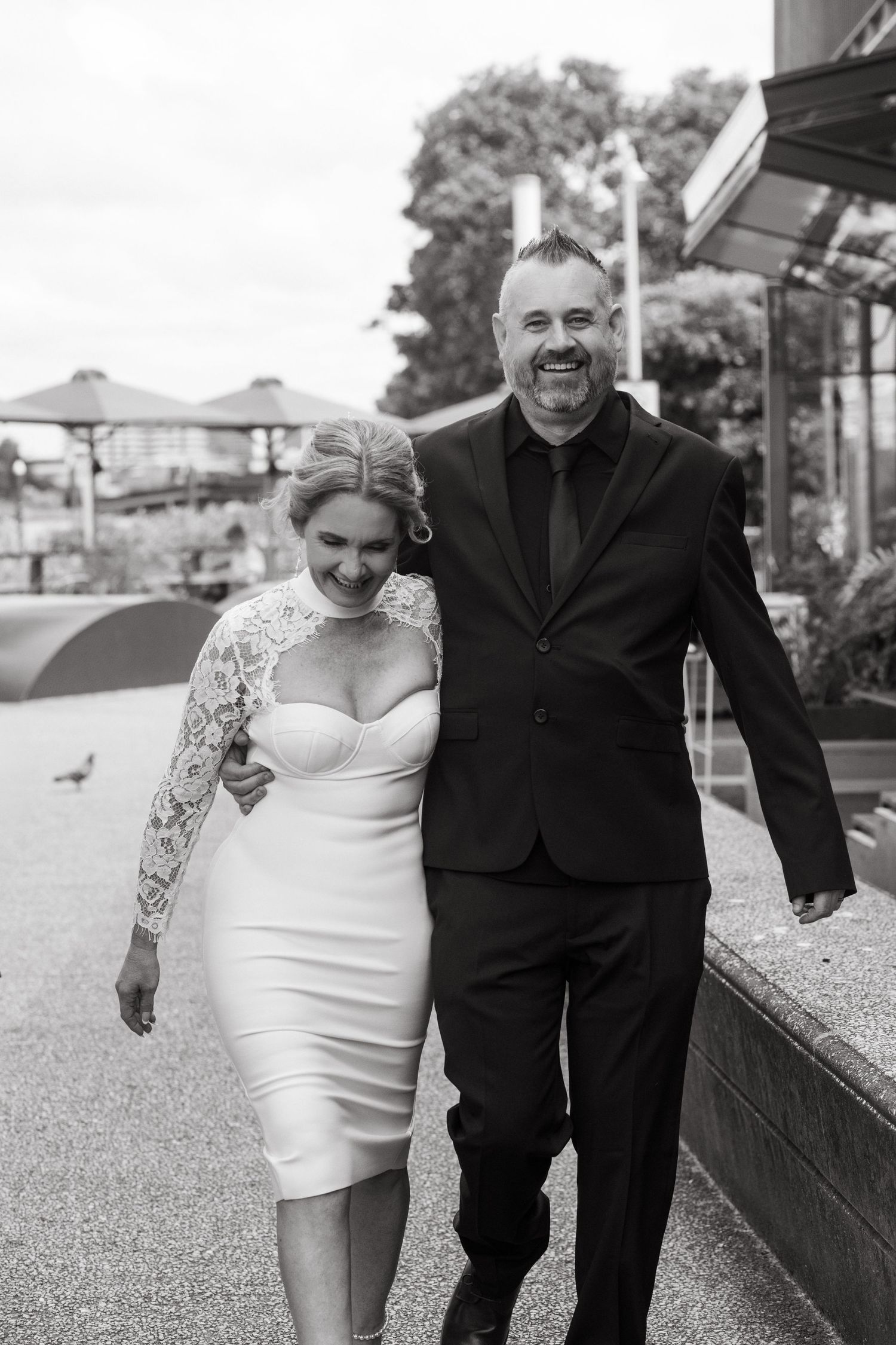 A black and white wedding photo series showing a couple walking together in formal attire.