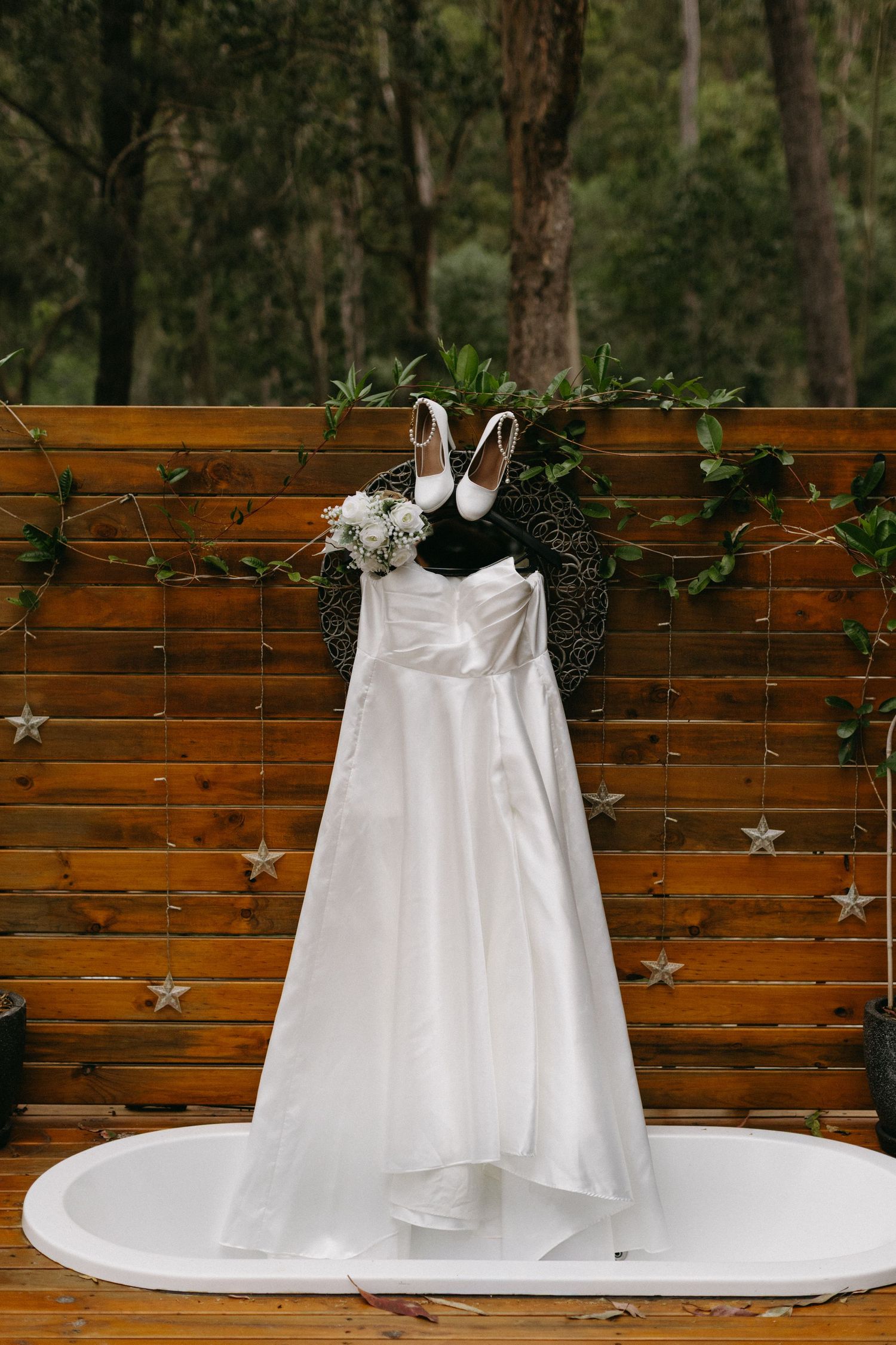 White wedding dress displayed against rustic wooden wall with star decorations.