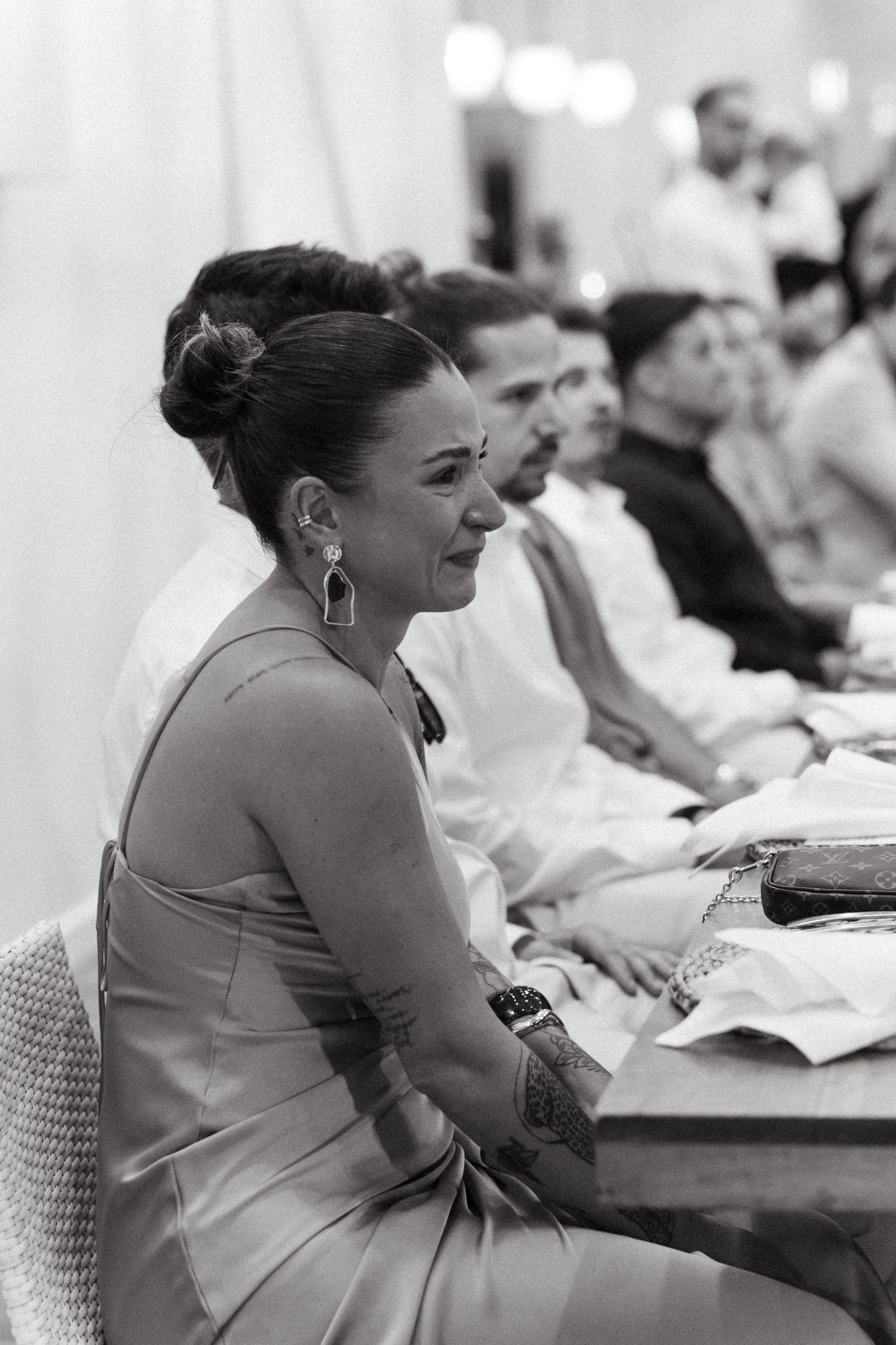 Wedding guests seated at reception tables showing emotional reactions.