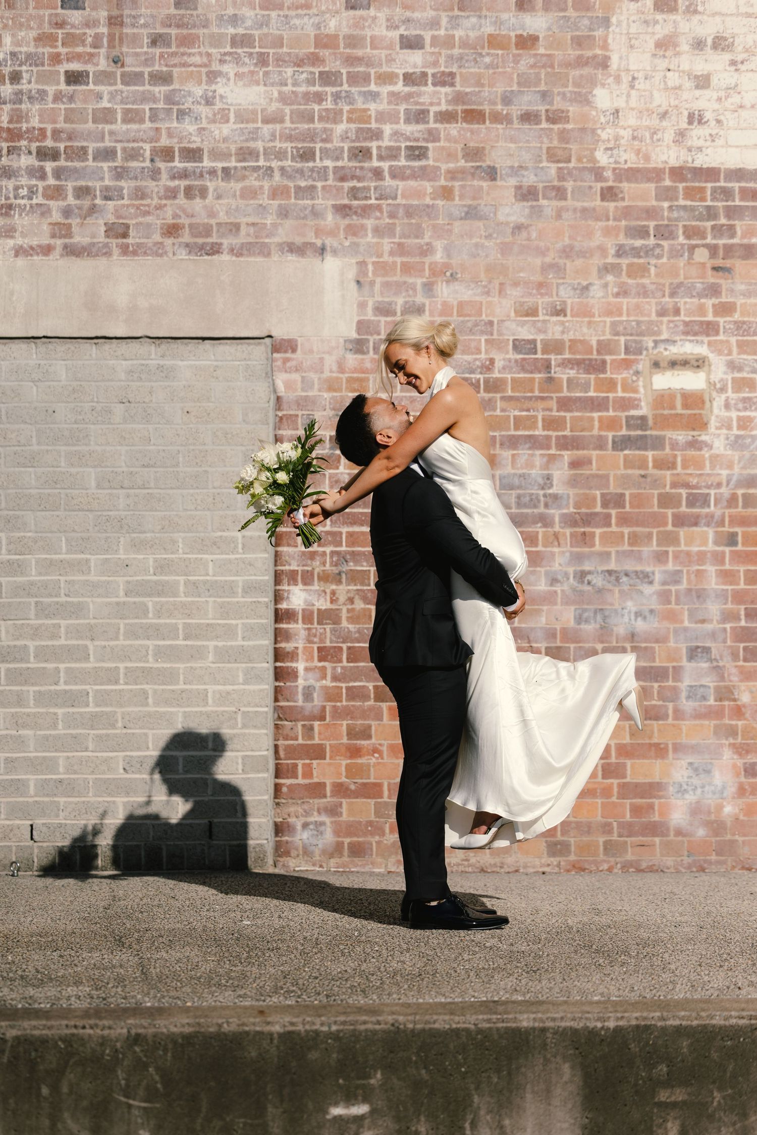A series of artistic wedding poses against a rustic brick wall showing dramatic dips and romantic movements.