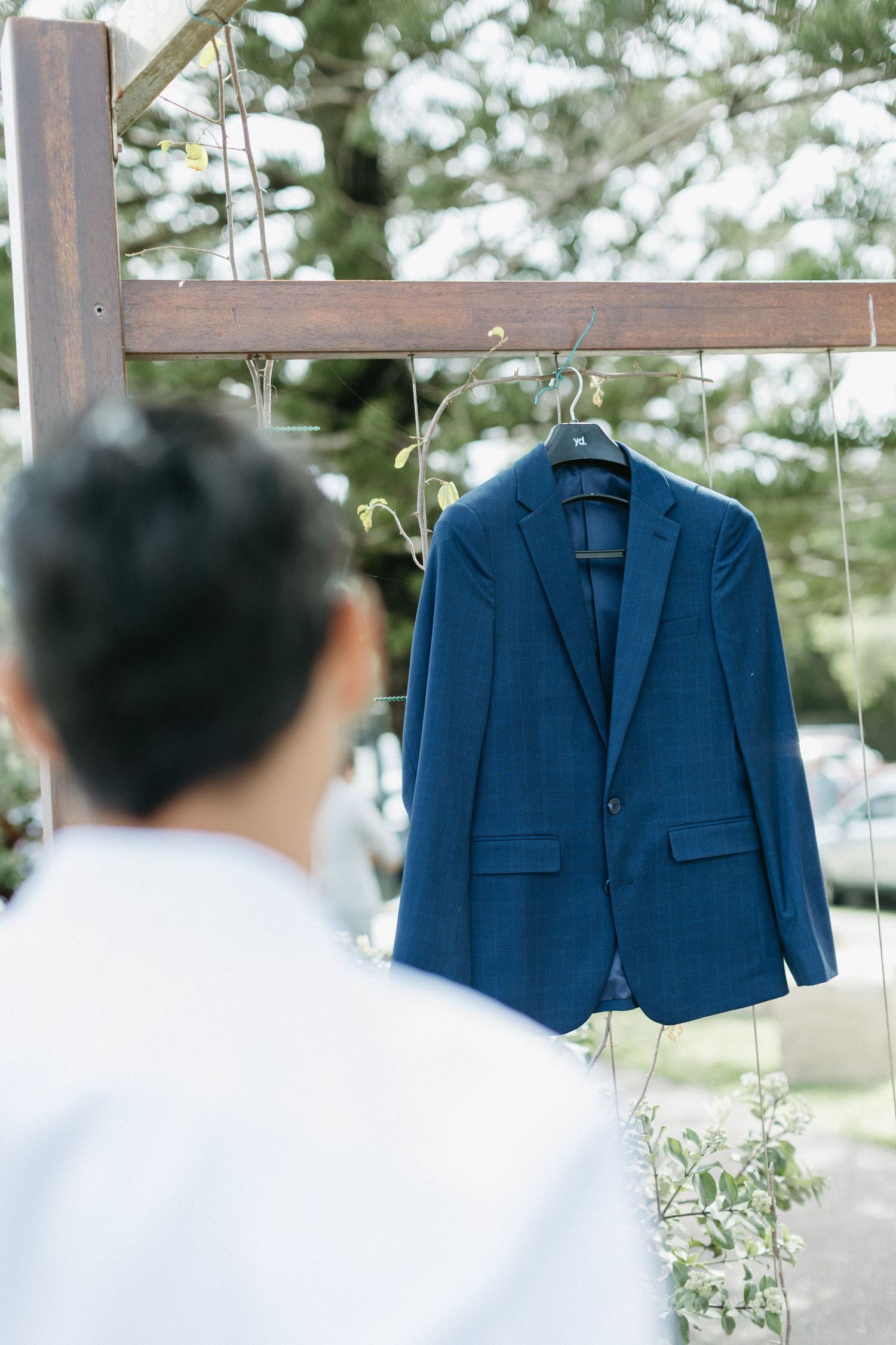 Blue suit jackets hang on display at an outdoor wedding venue.