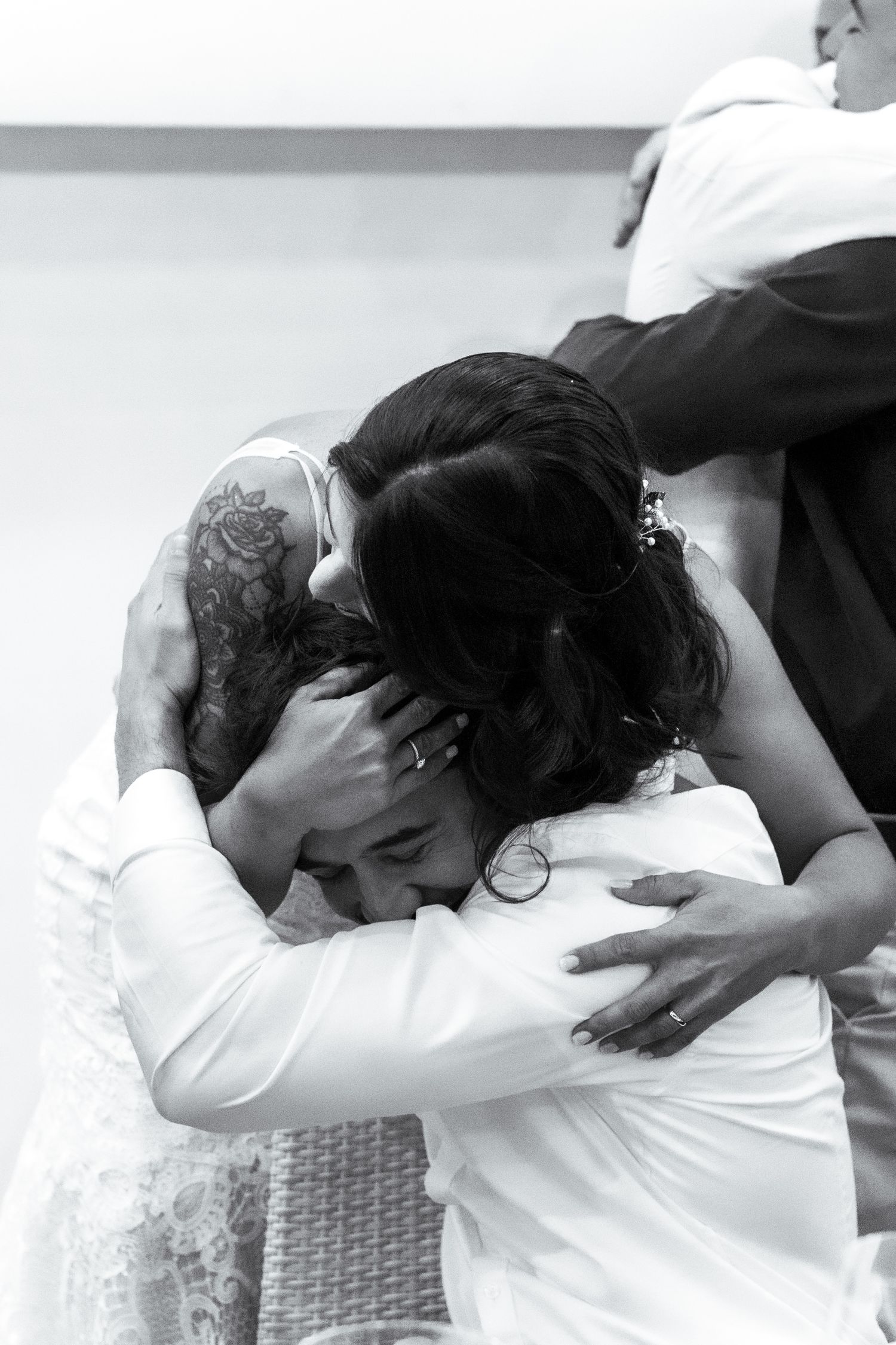 Emotional group hug captured in black and white at formal event.