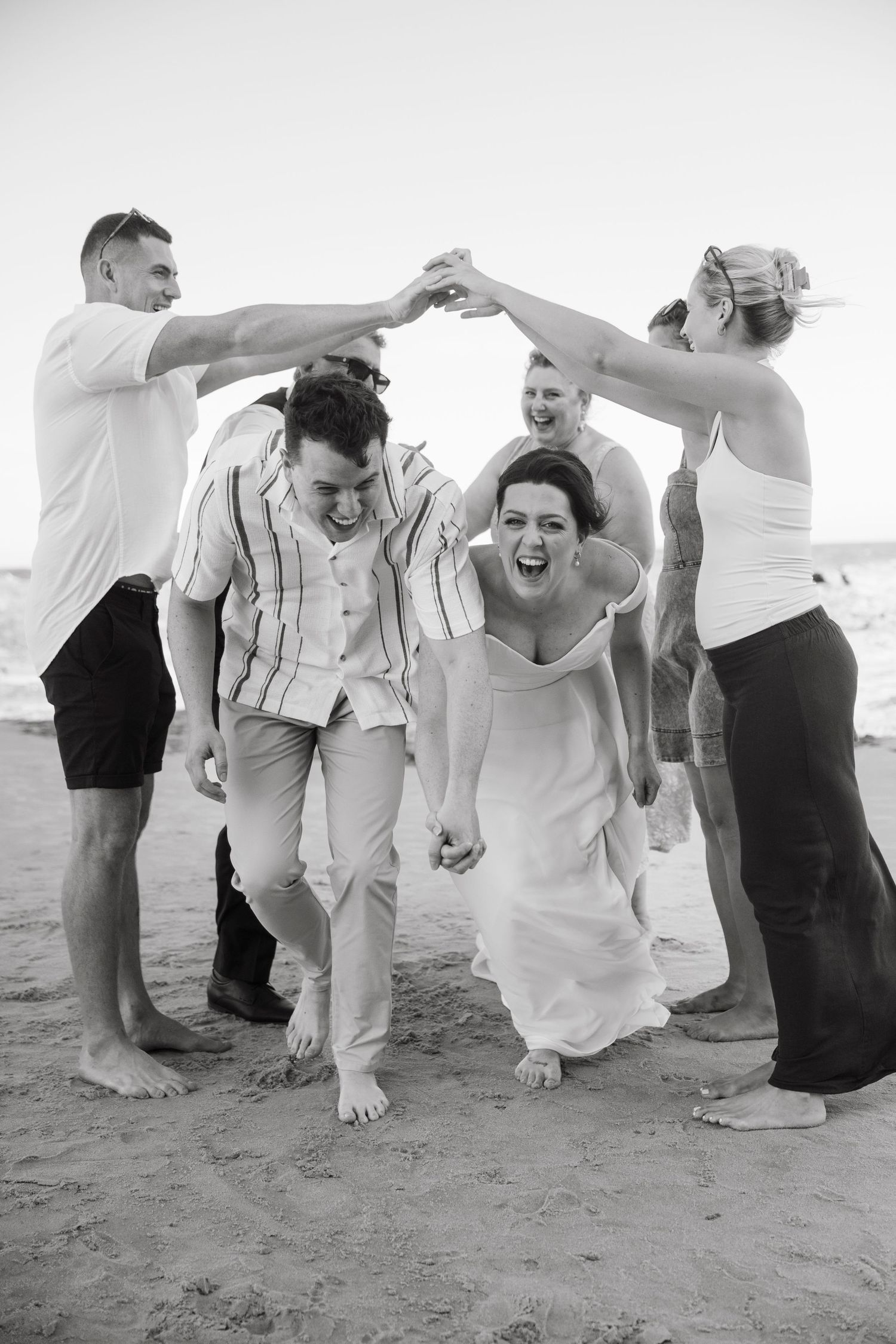 A sequence of black and white photos showing a couple playfully dancing and spinning on the beach.