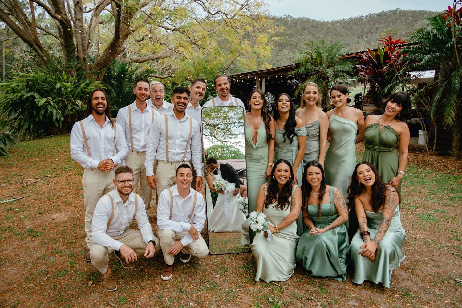Wedding party group photo with bridesmaids and groomsmen in light colored attire.