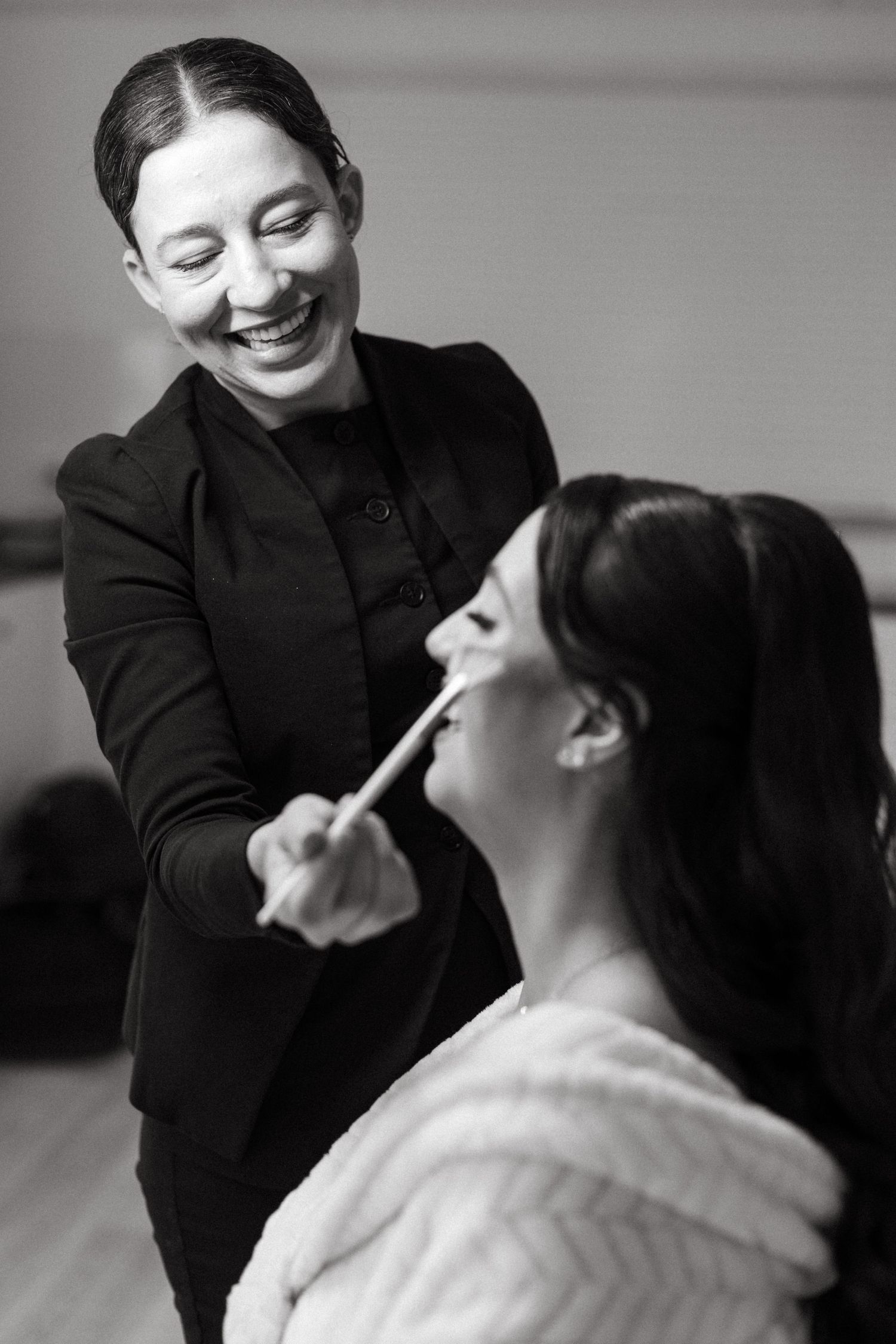 Black and white candid photos showing joyful laughter during wedding preparations.