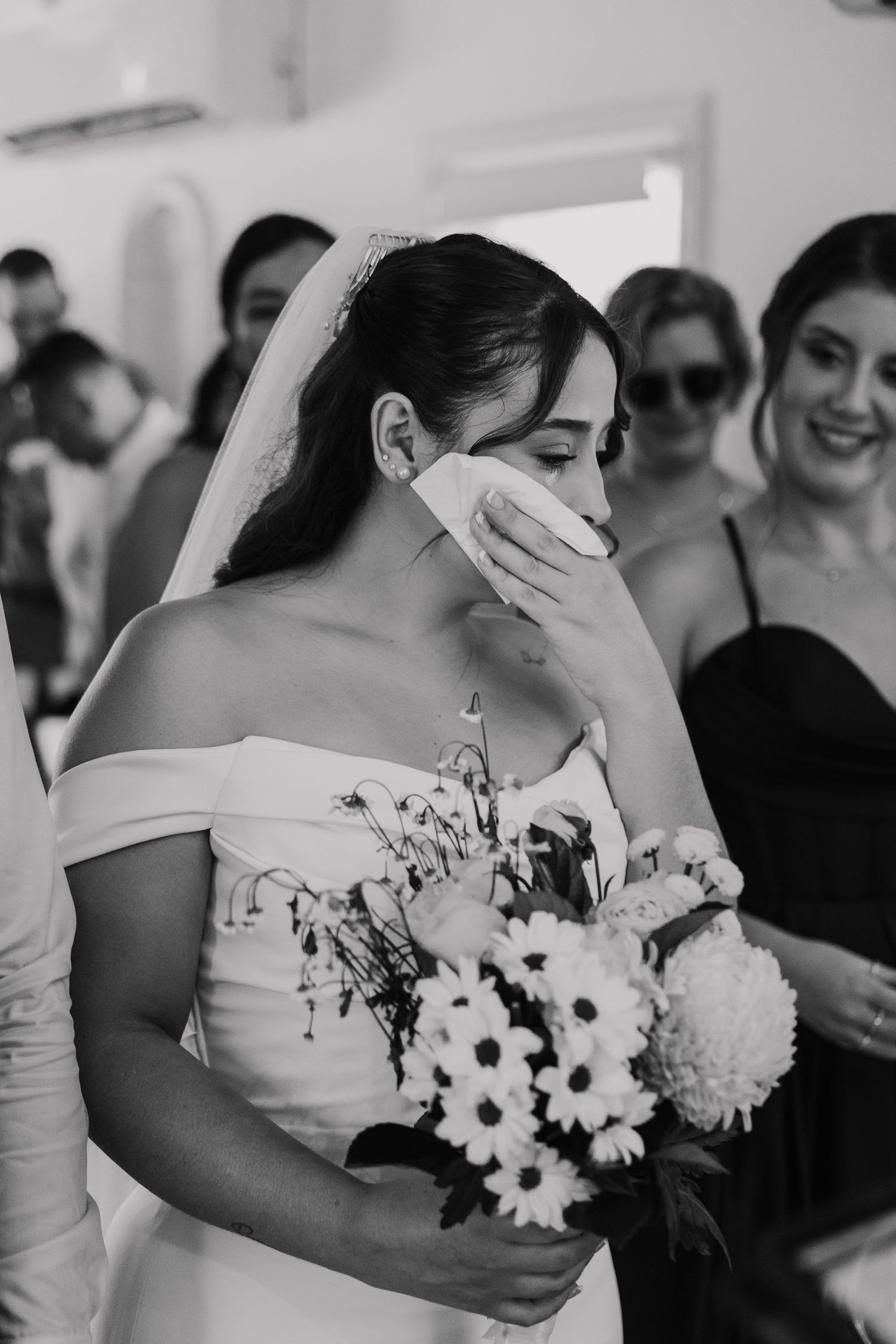 Bridesmaids in white dresses hold black and white floral bouquets during an elegant wedding ceremony.
