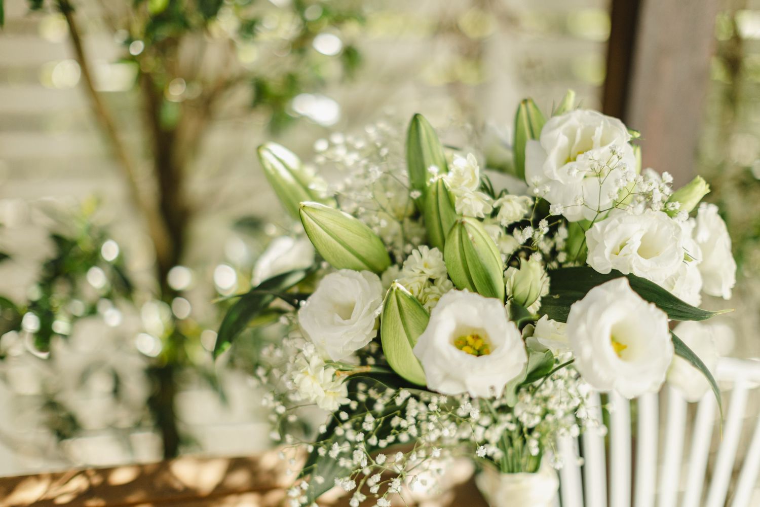 White floral arrangements with roses and baby's breath decorate an elegant outdoor wedding reception setting.