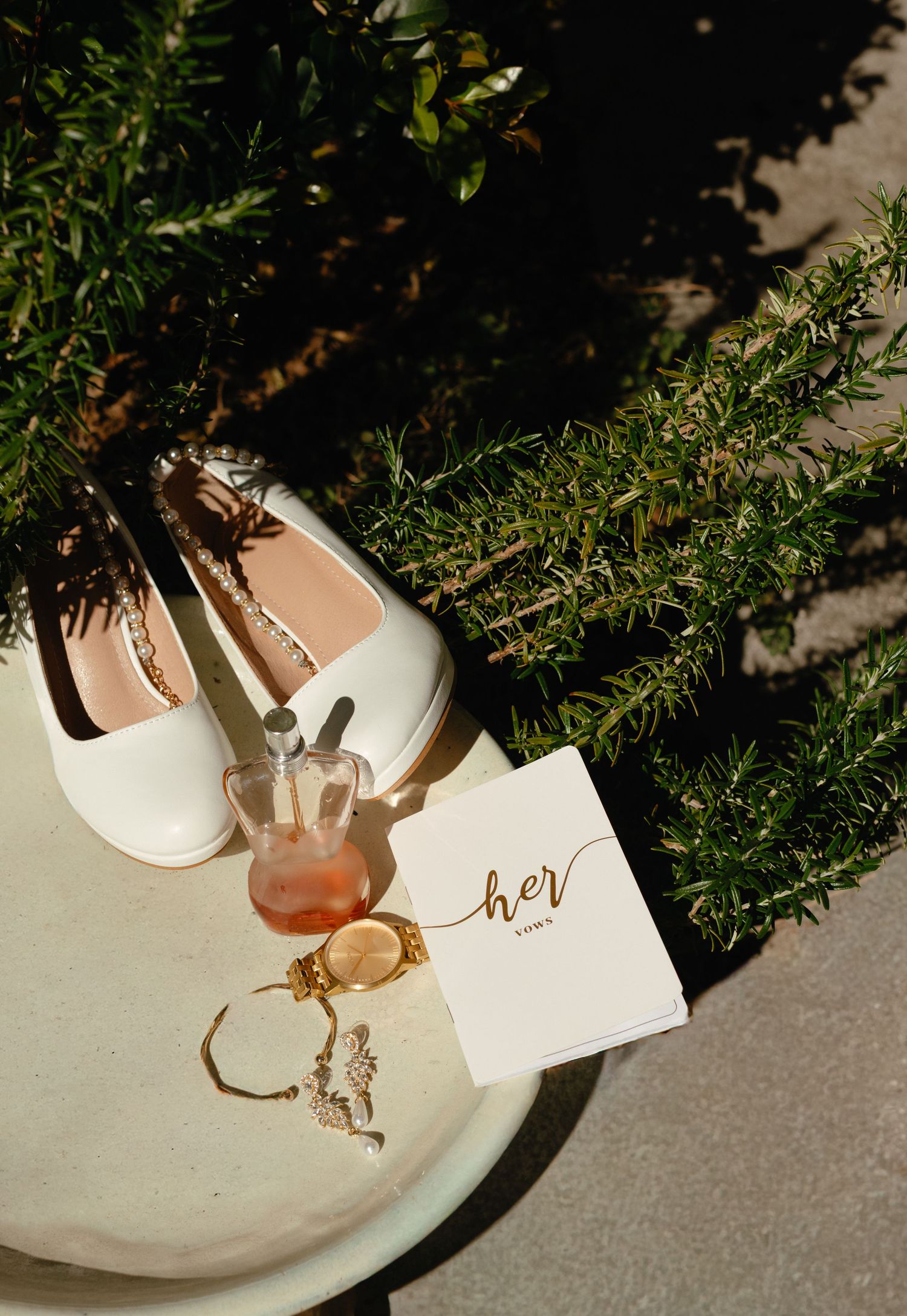 Decorative wedding details with drinks and place cards arranged on white ceramic plates among greenery.