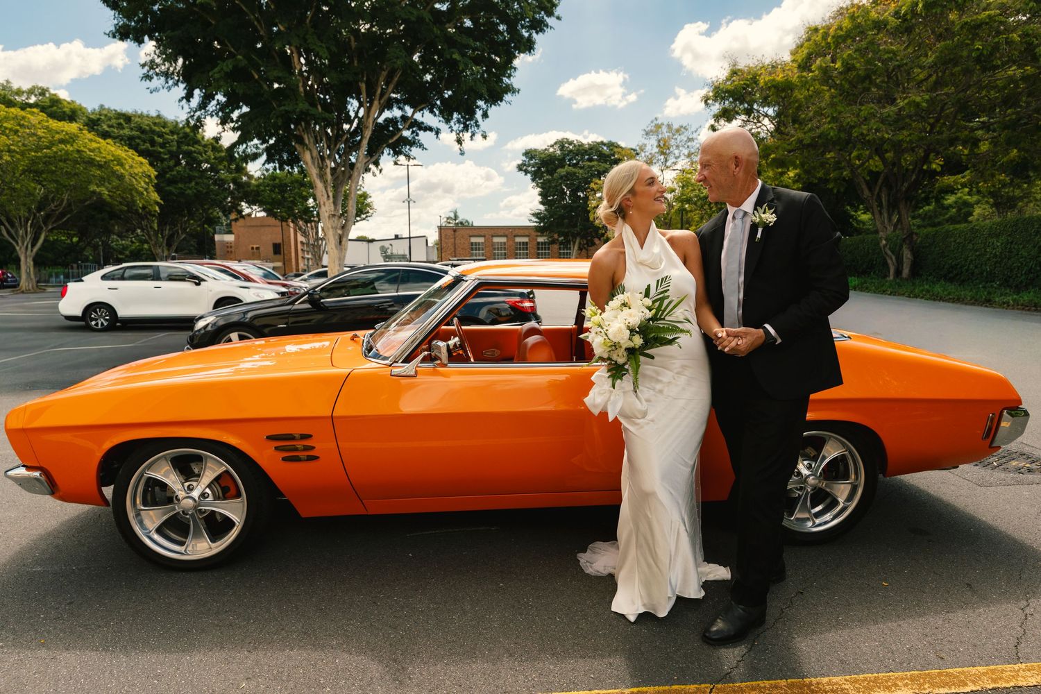 An orange classic convertible car is featured in a series of wedding photos outside a venue.
