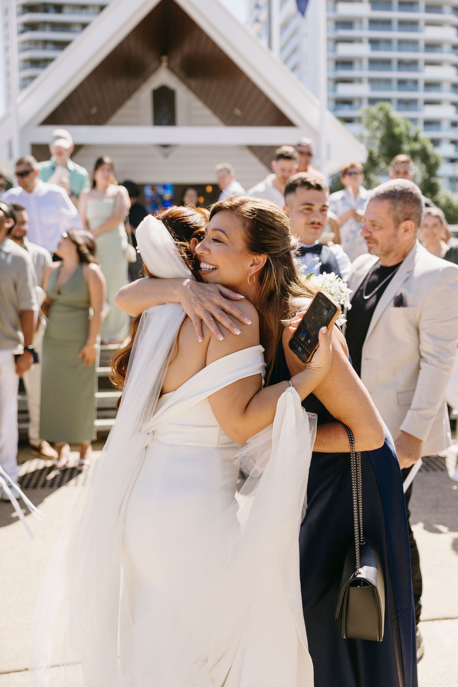 Wedding guests in navy and white attire share a toast with champagne flutes at an outdoor celebration.