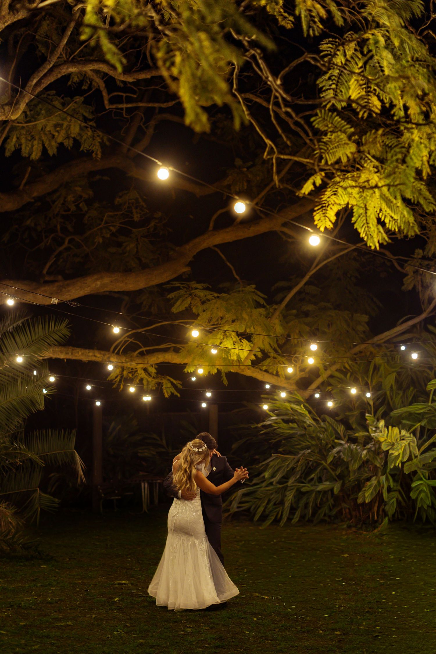A romantic evening wedding scene with string lights hanging from trees creating a magical atmosphere.
