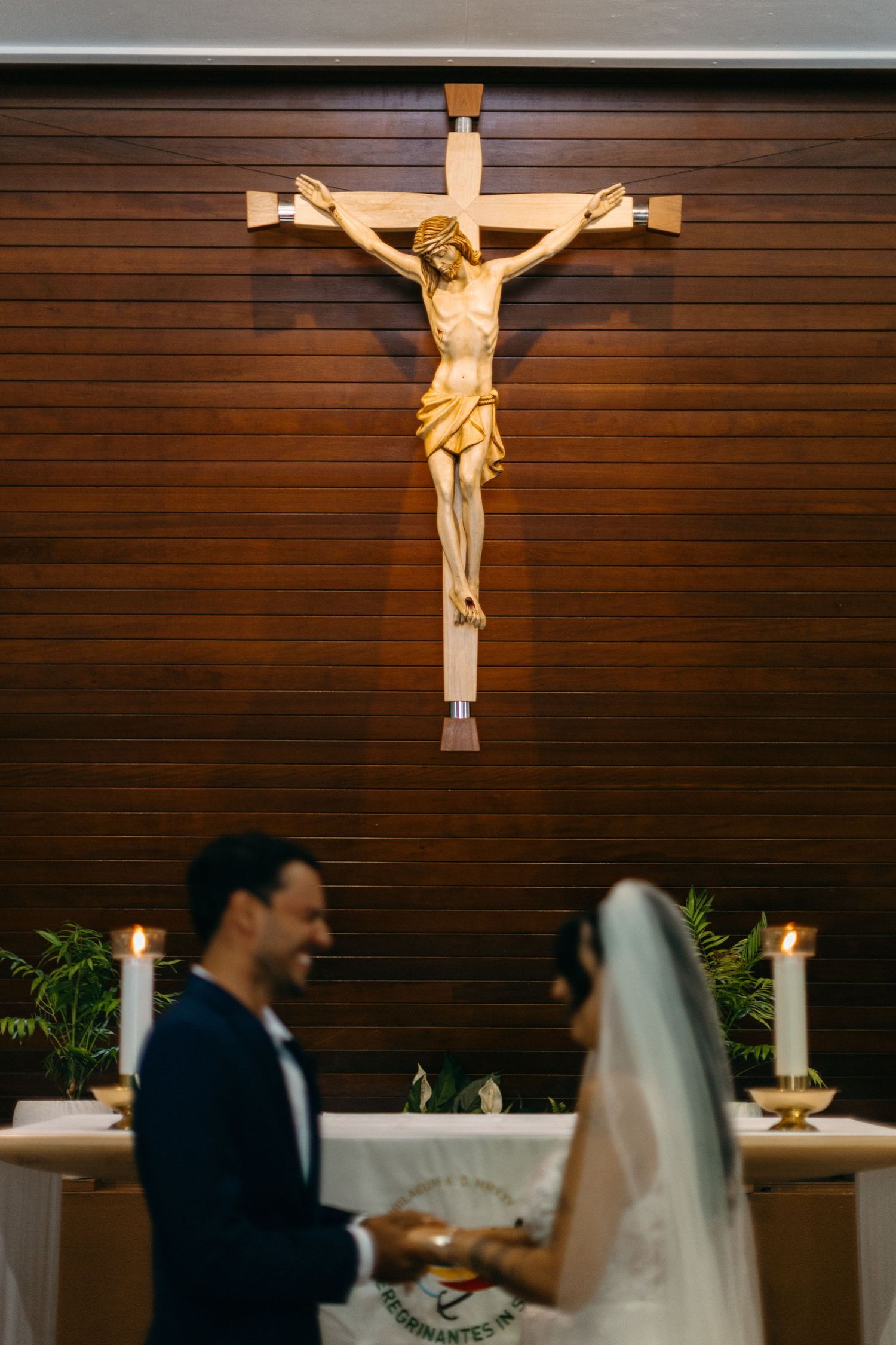 A traditional Catholic church wedding ceremony setting with a wooden crucifix on the wall.