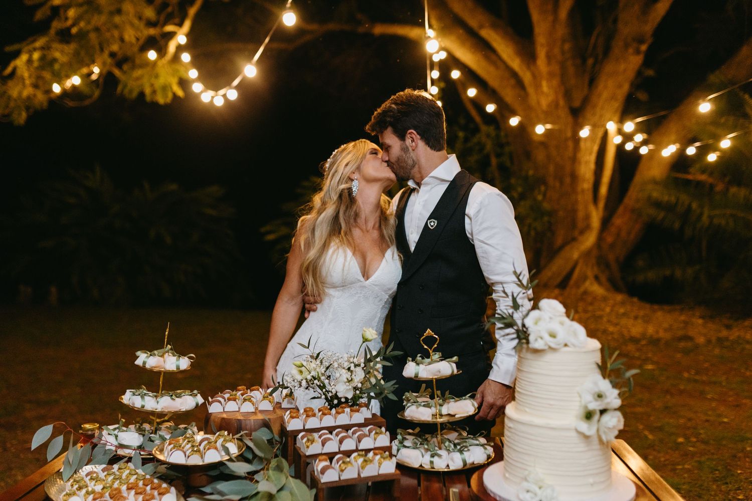 Elegant outdoor wedding reception under tent with string lights at dusk.