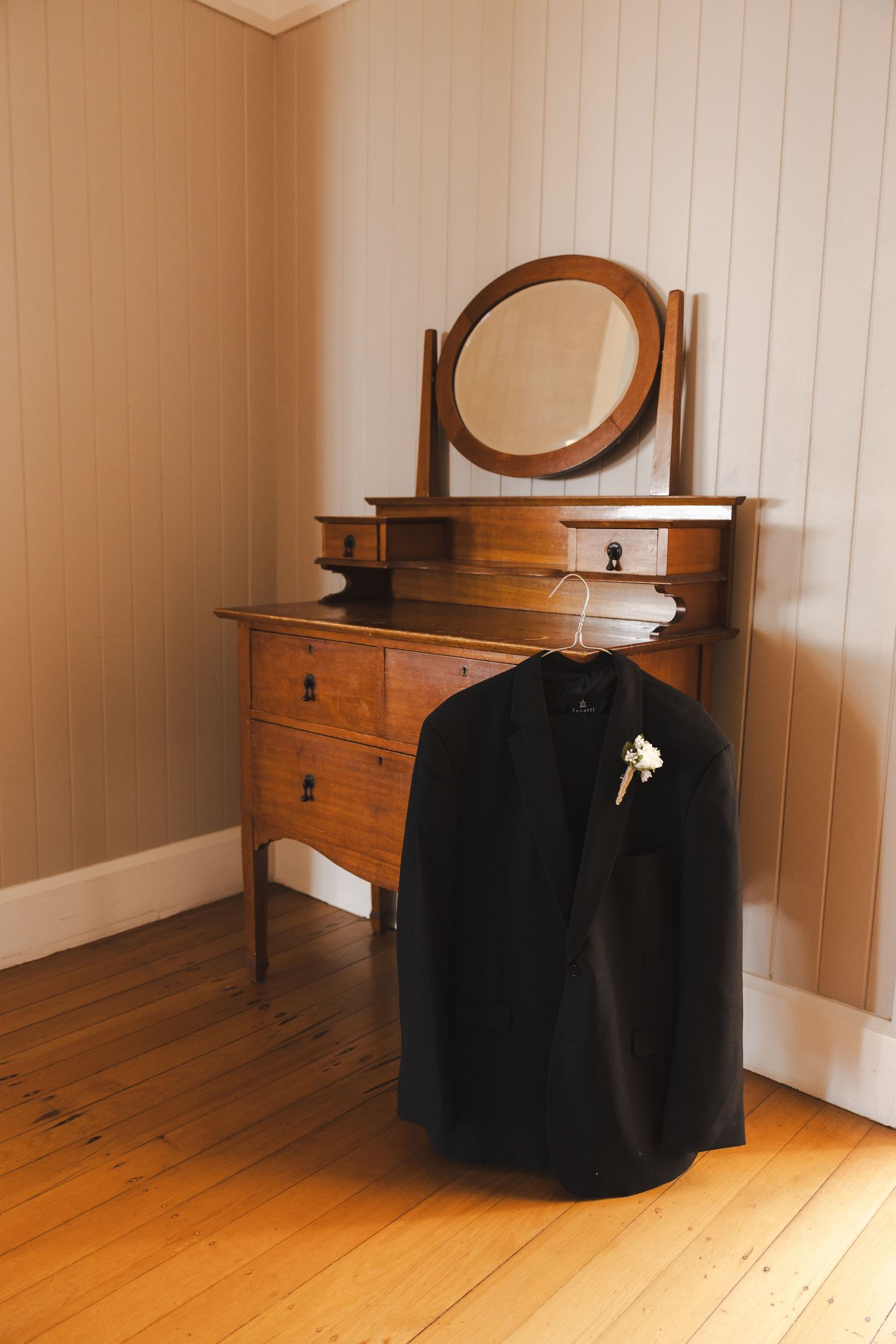 Vintage wooden dressing tables with oval mirrors lined up against a white wall.