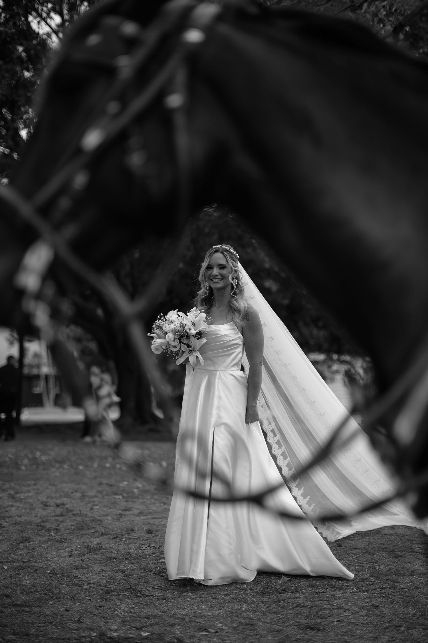 Artistic black and white wedding dress portrait on grassy field.