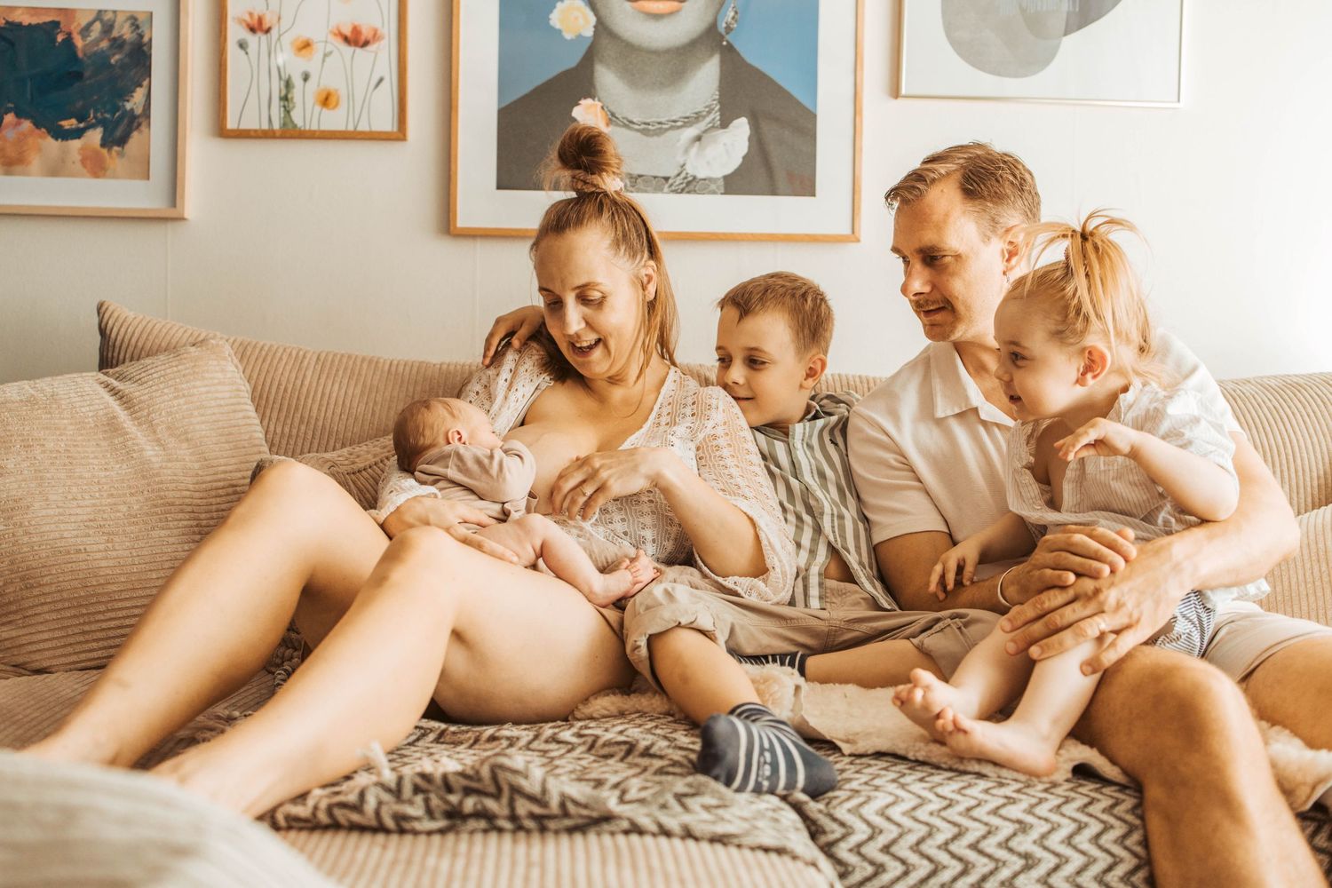 Familj myser med en nyfödd bebis i soffan med en bebis som ammar.