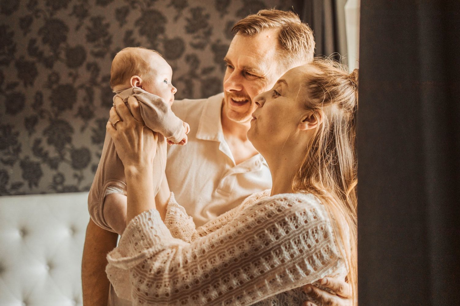 Bild på mamma och pappa med en nyfödd bebis som hålls upp