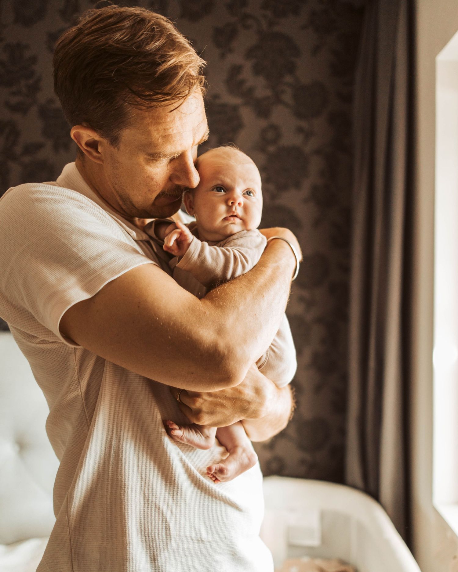 Pappa pussar på sitt nyfödda barn i sovrum.