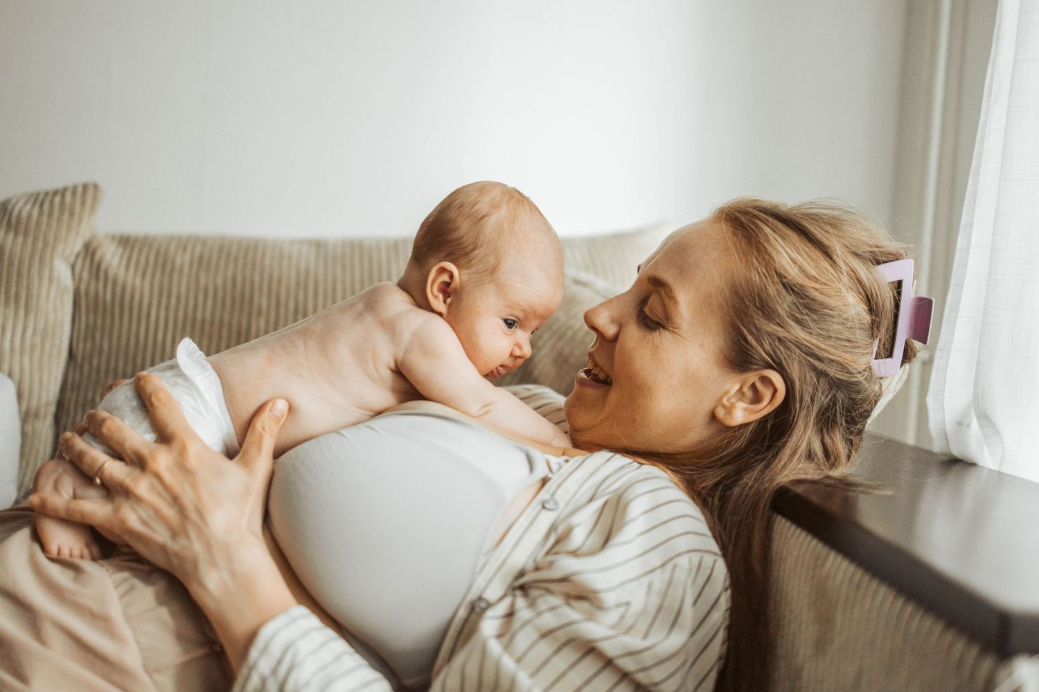 Mamma och nyfödd bebis myser i soffan.