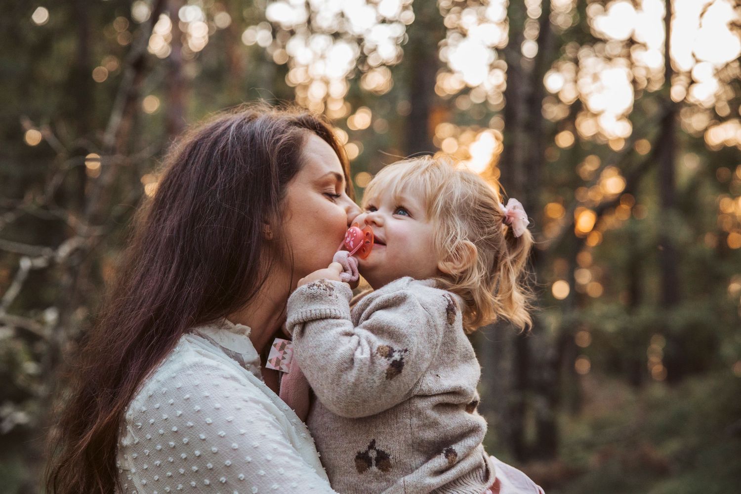 Familjefotogarfering mamma pussar dotter i skogen.