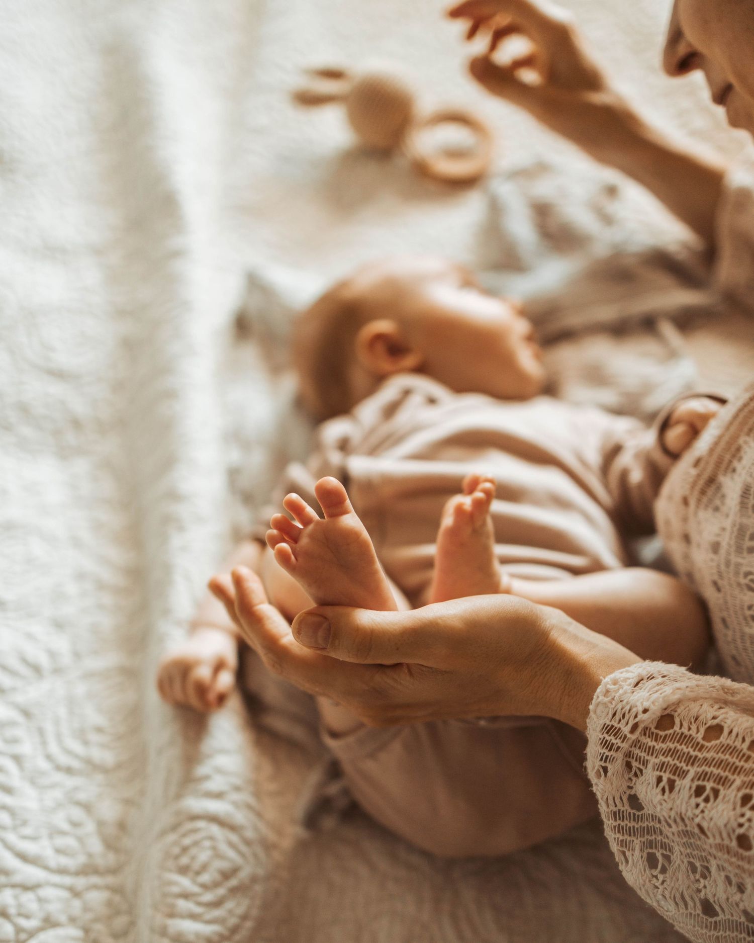 Bebisfötter och mamma myser i säng.