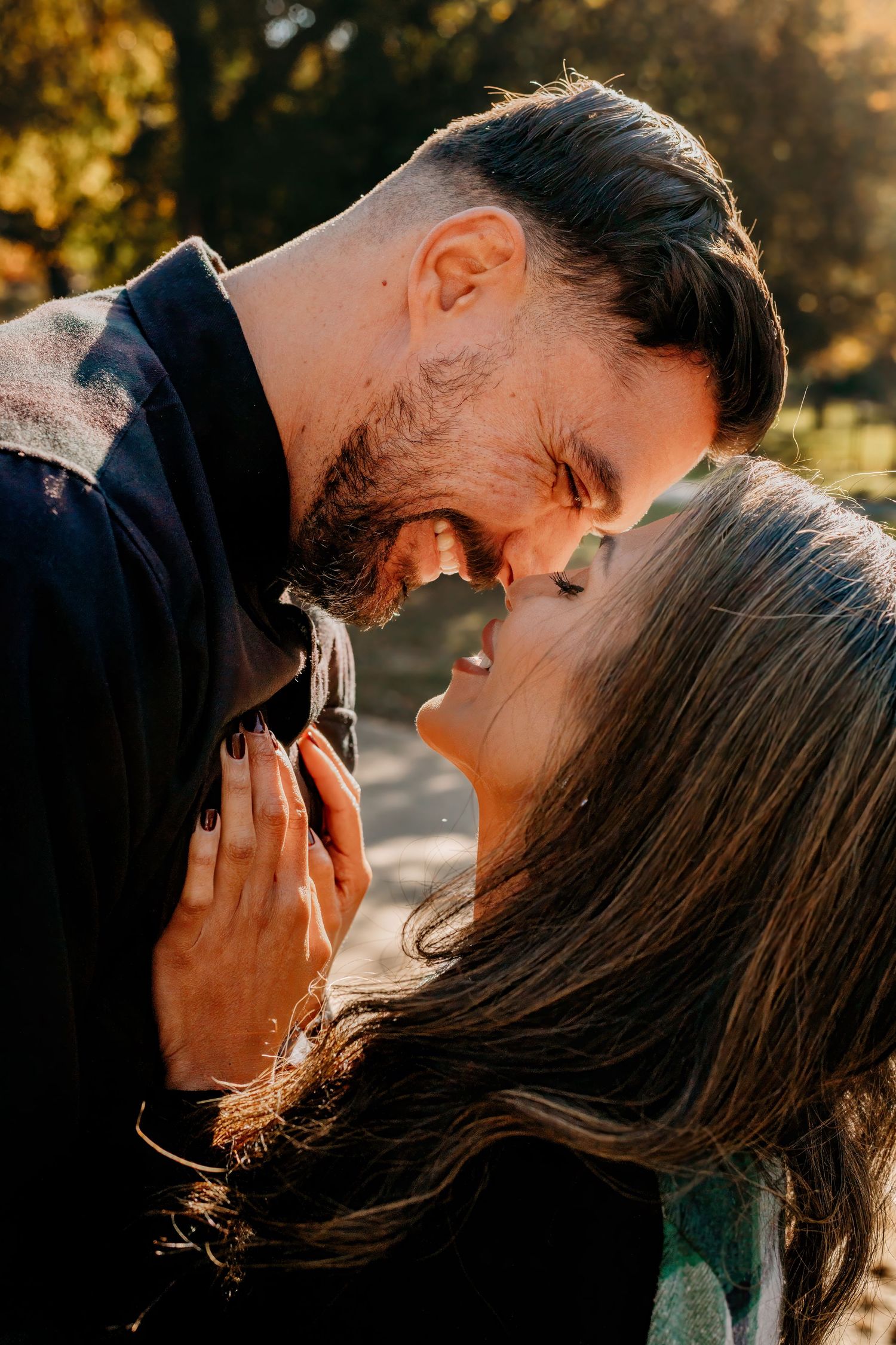 A tender moment between a couple laughing together in warm sunlight.
