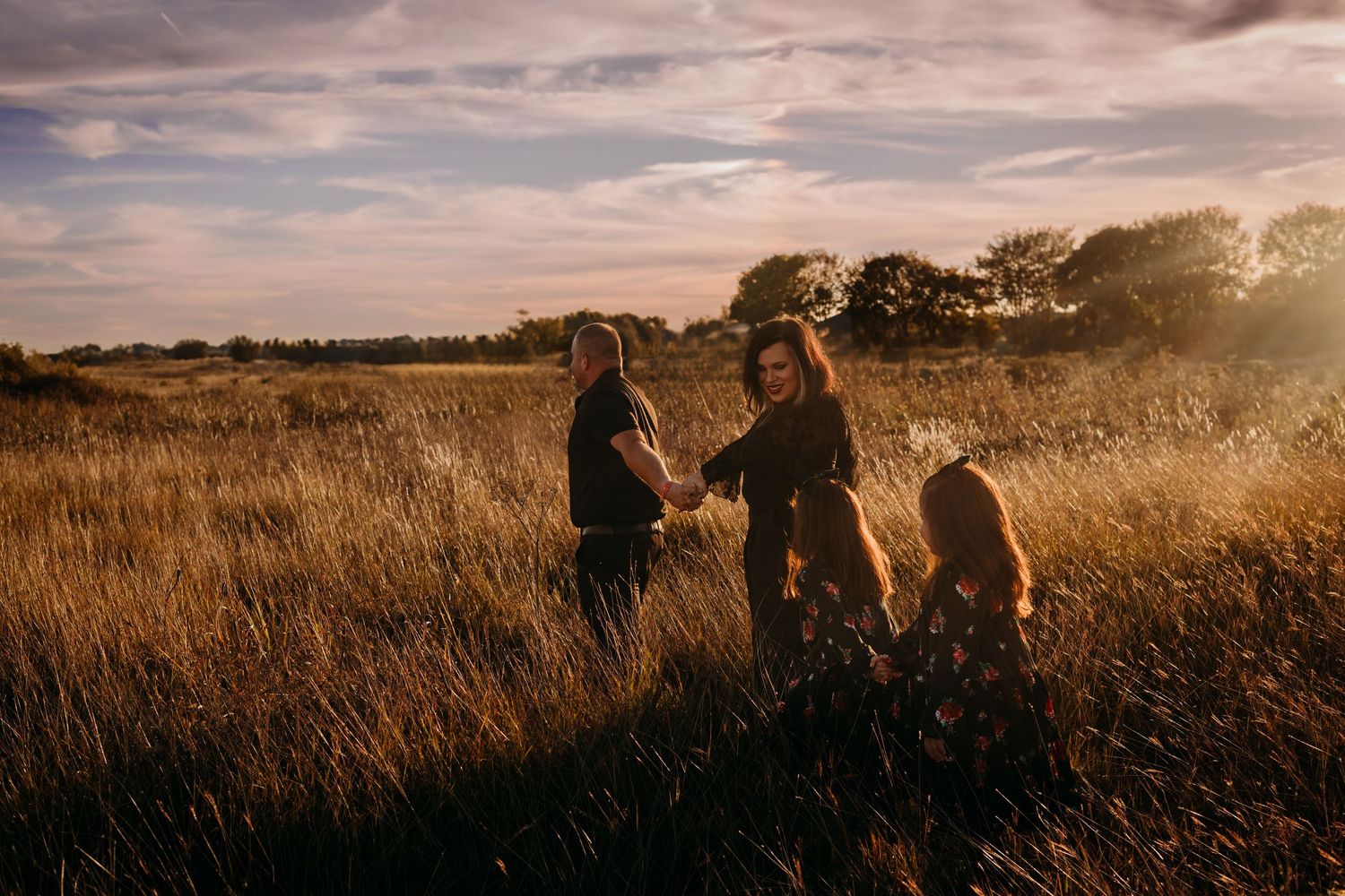 Scenic sunset photography session in a golden grass field with dramatic clouds.