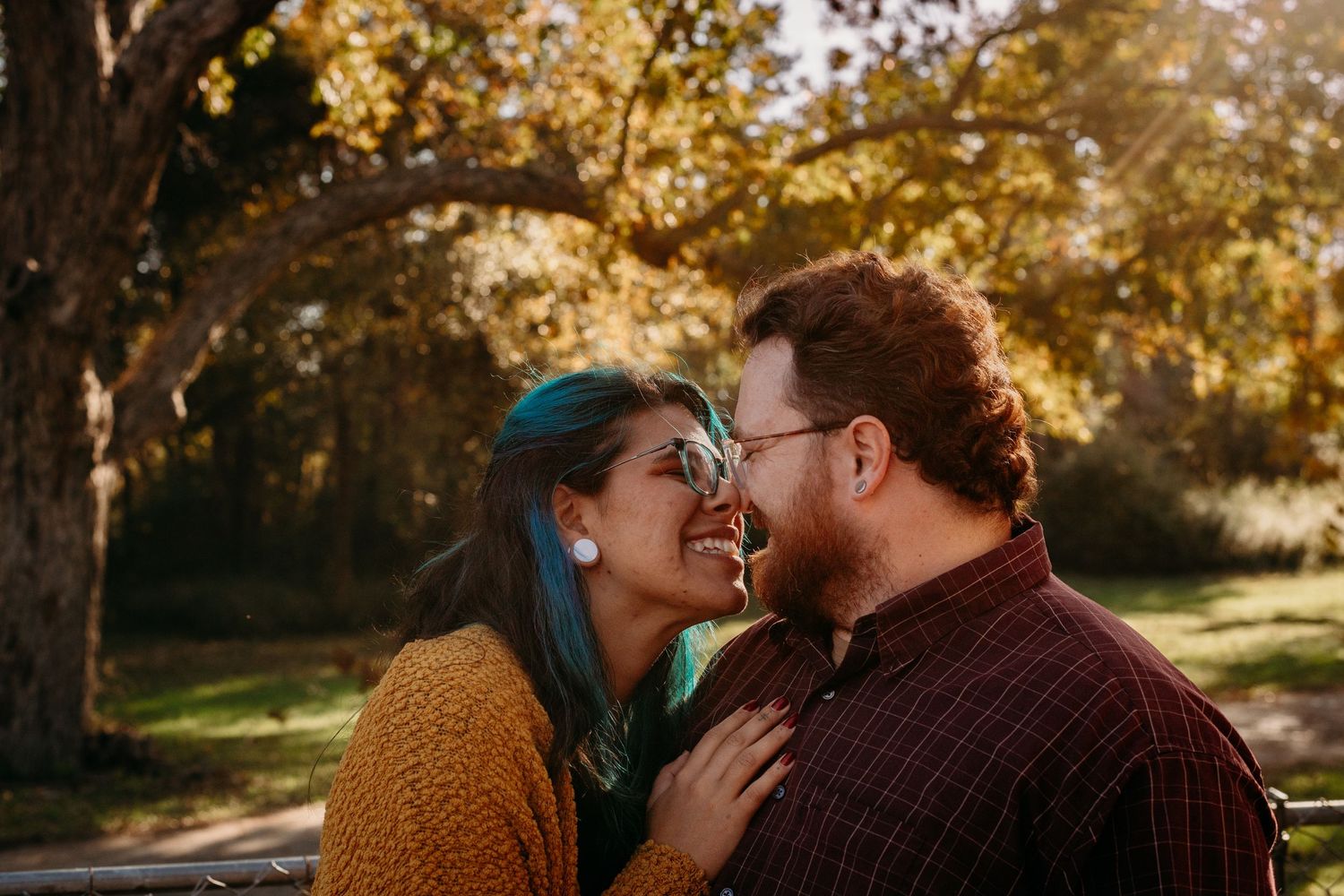 A couple shares an intimate laughing moment outdoors during golden hour.