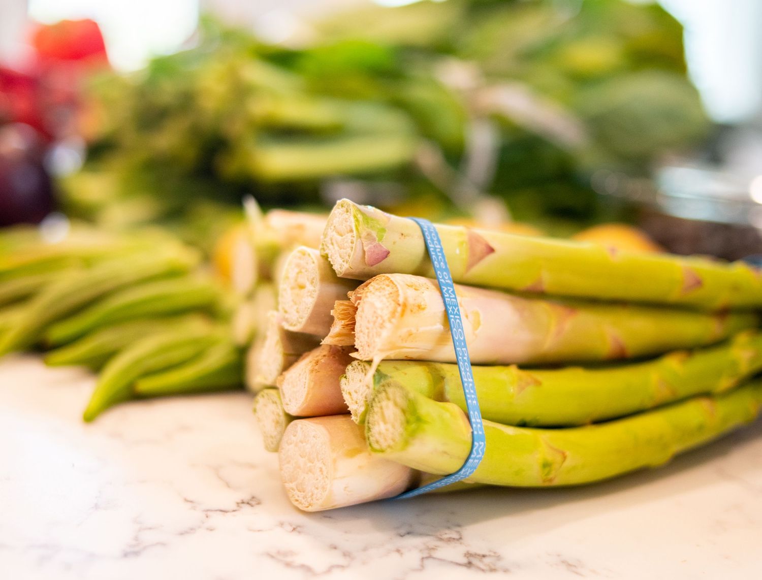 Bundle of fresh green asparagus spears tied together with blue rubber bands.