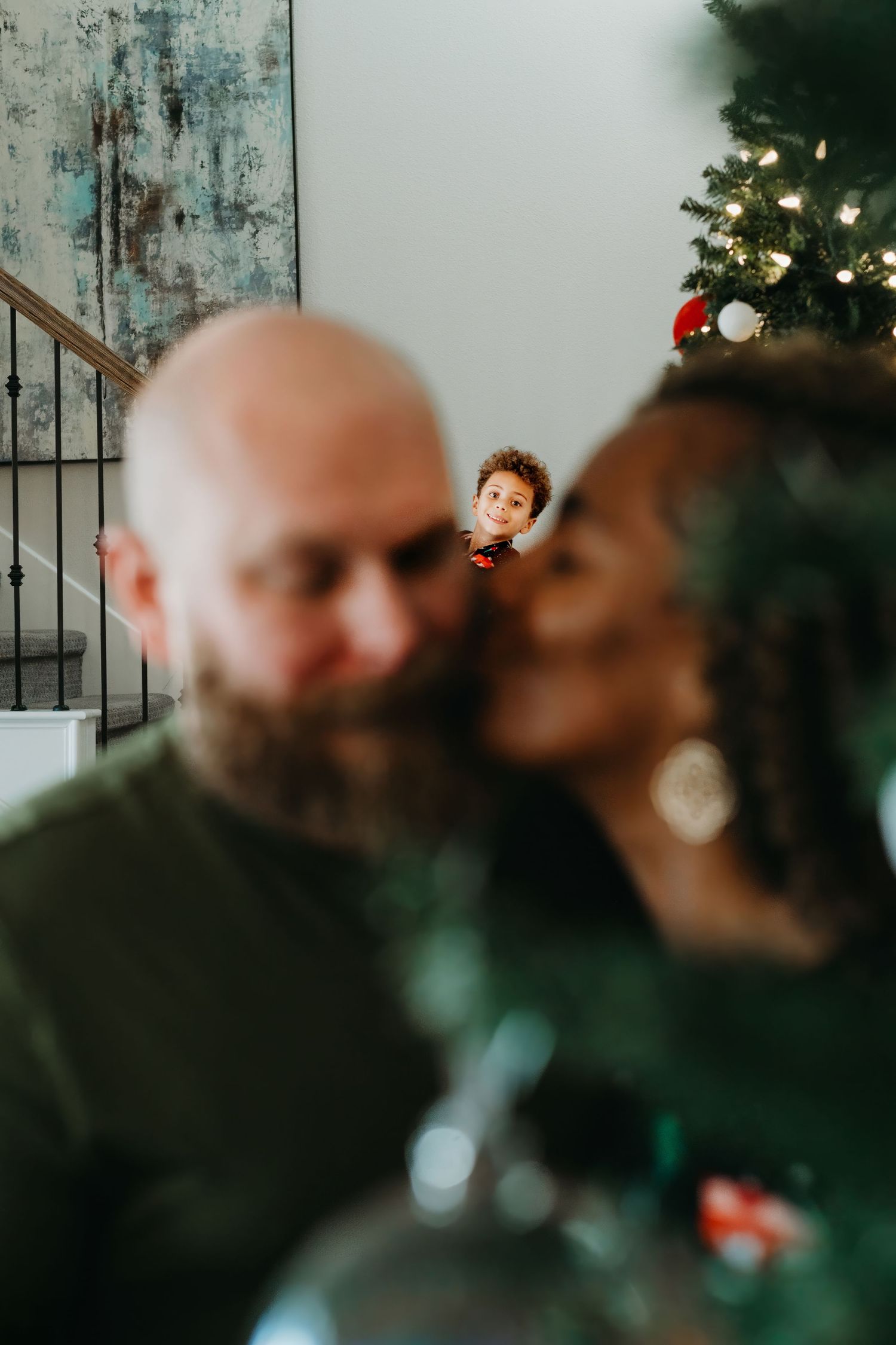An intimate family holiday portrait with a Christmas tree in the background.