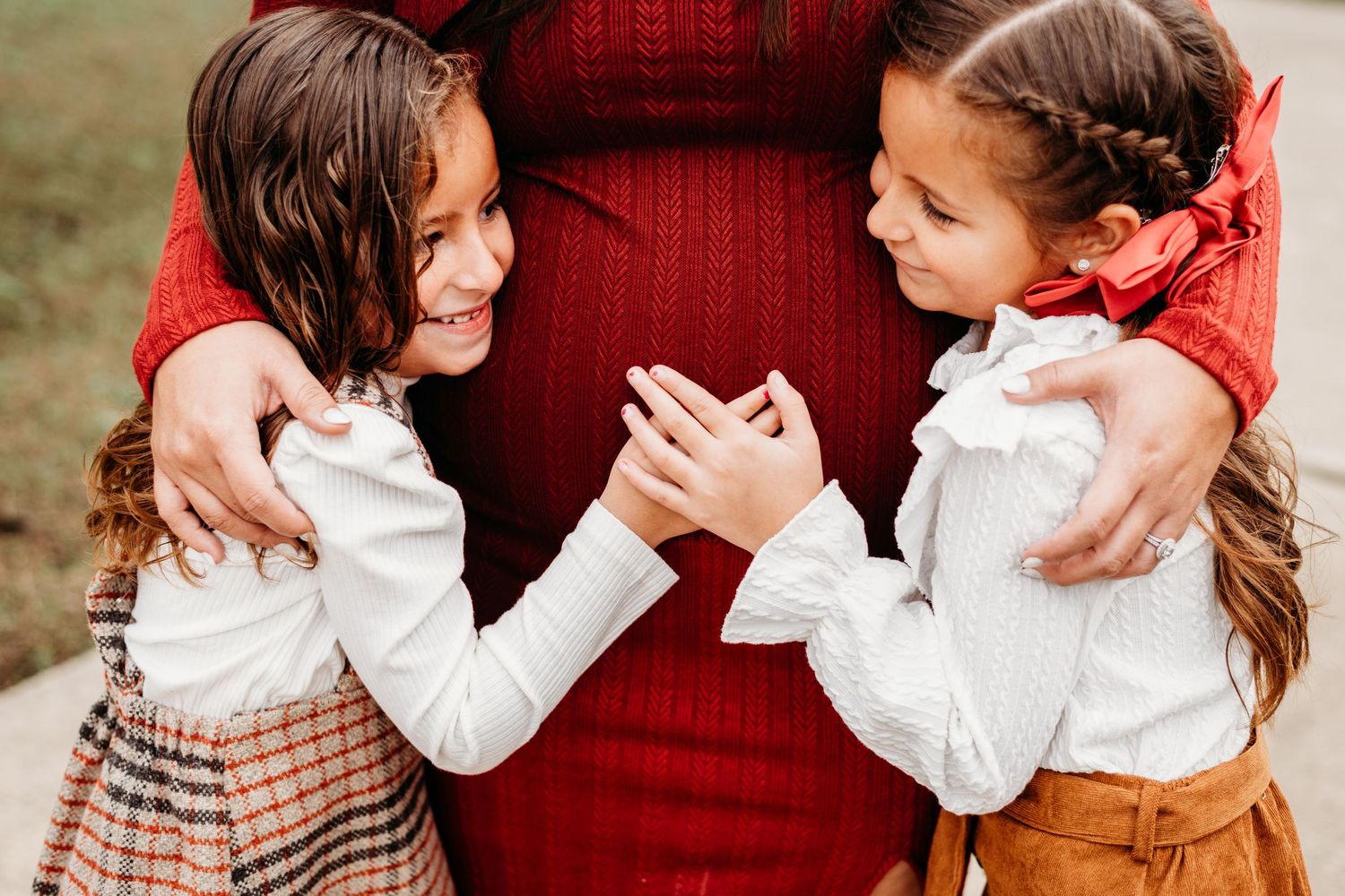Sweet outdoor family moment captured in autumn colors with a red sweater and white blouses.