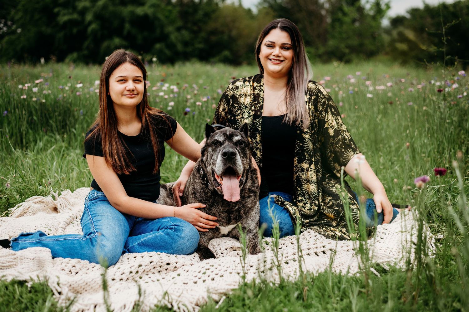 Friends relaxing on a blanket in a wildflower meadow during summer.