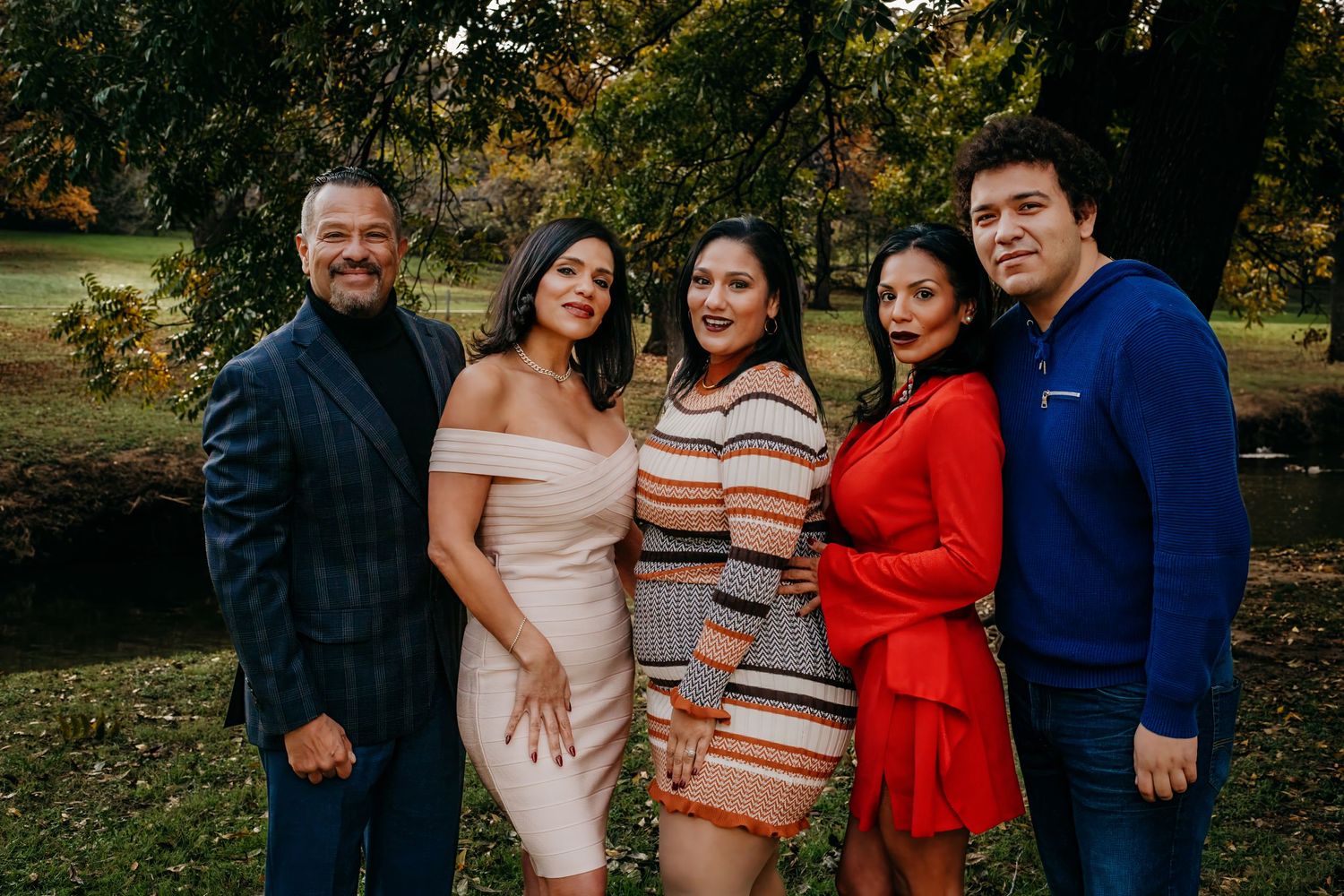 A group poses together outdoors wearing stylish outfits in a garden setting.