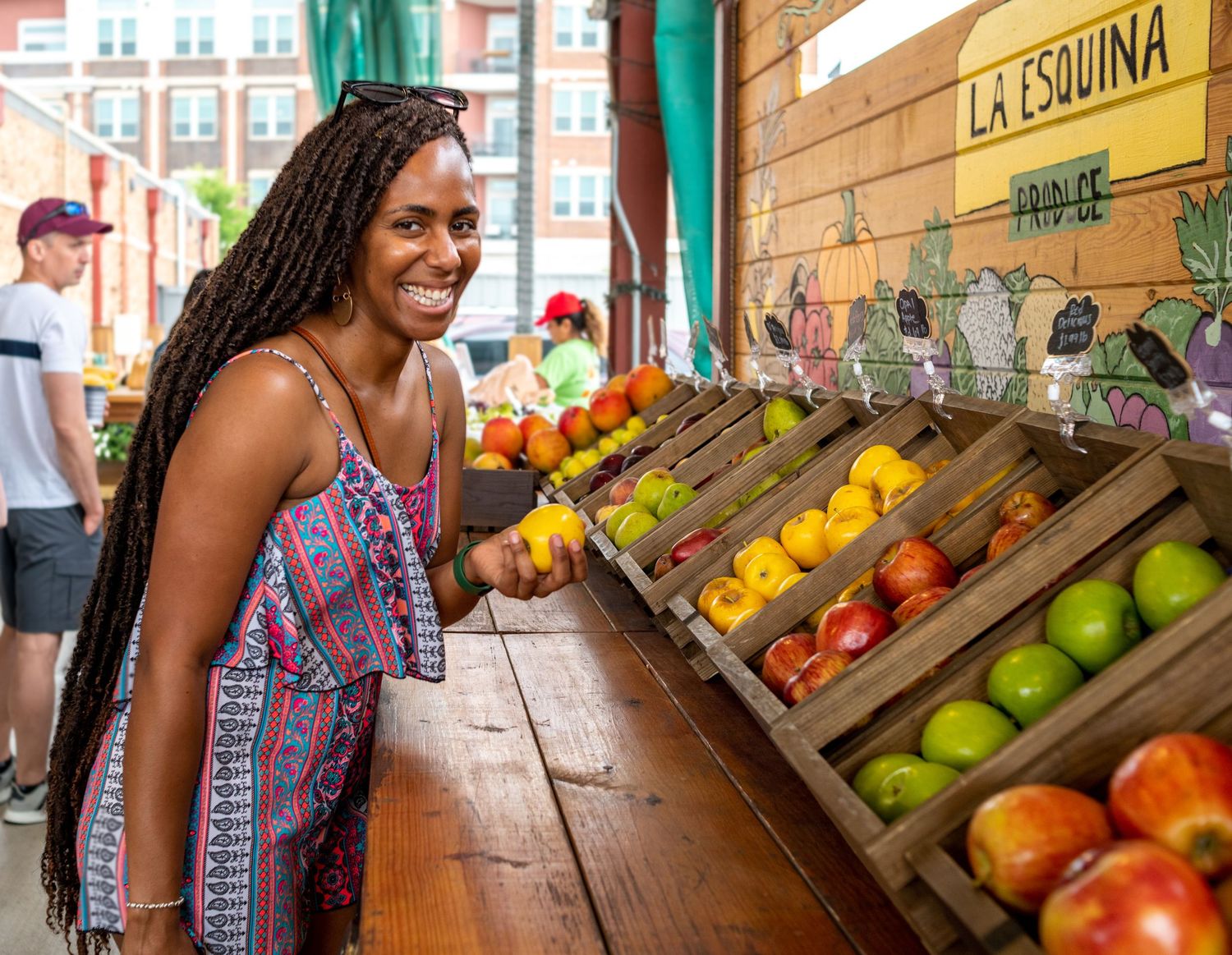 Shopping for fresh produce at a local market stand with tropical fruits and vegetables on display.
