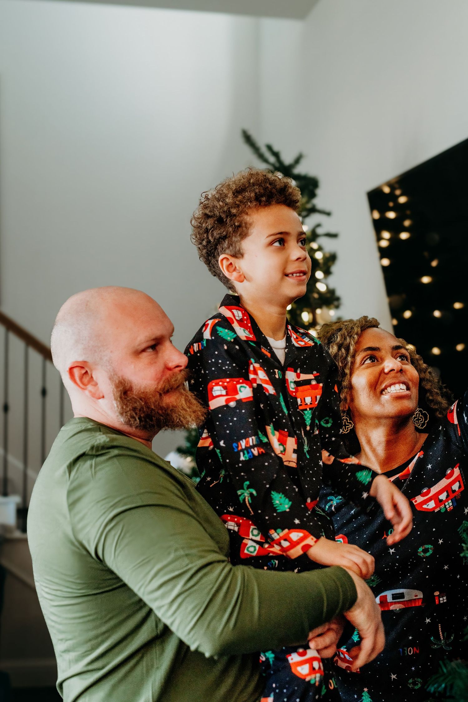 A joyful family moment during Christmas time with decorative lights in the background.