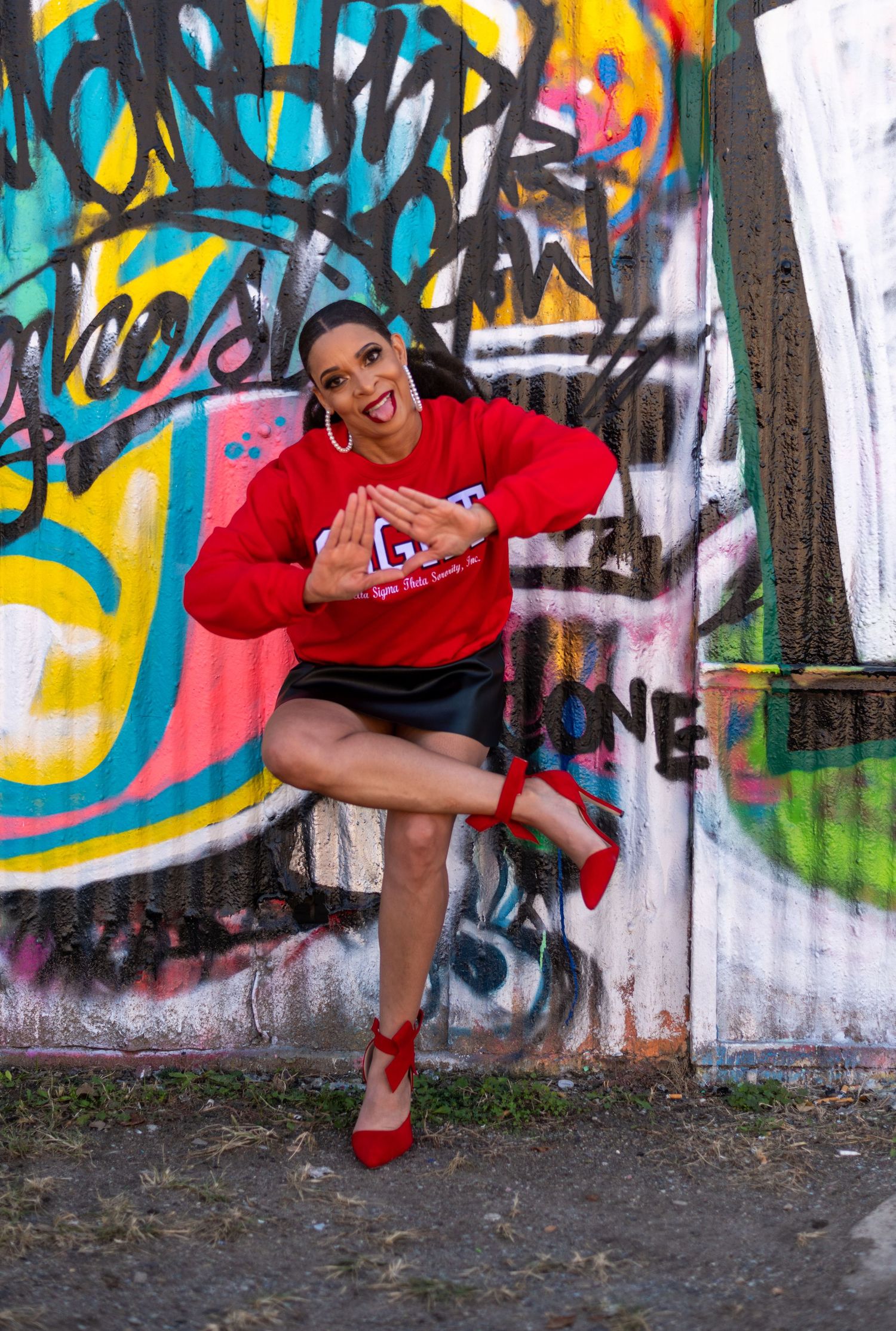 Dynamic dance poses in front of vibrant graffiti wall wearing red outfit.
